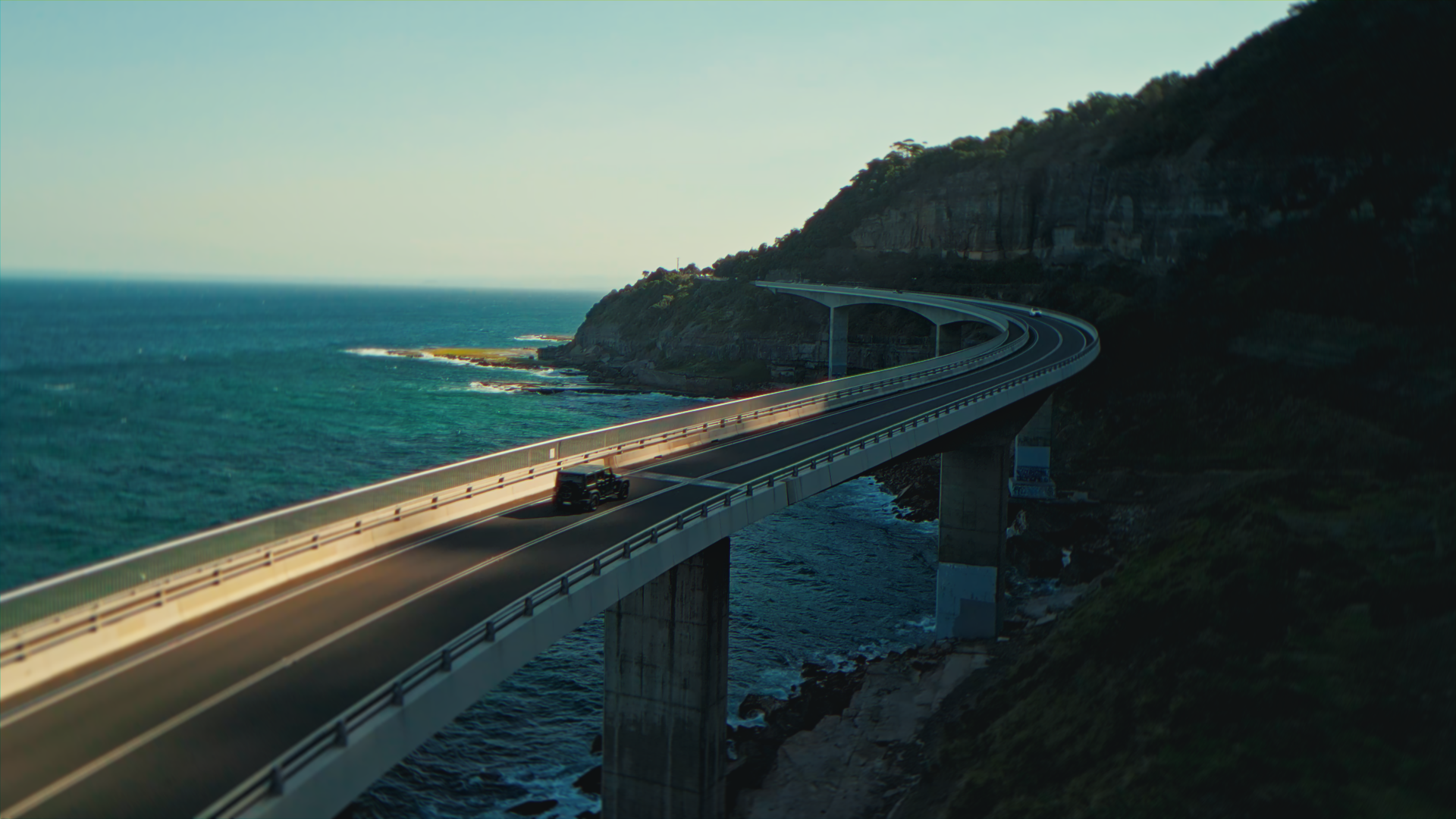 Un ponte sopra il mare con un'auto che viaggia lungo la strada.