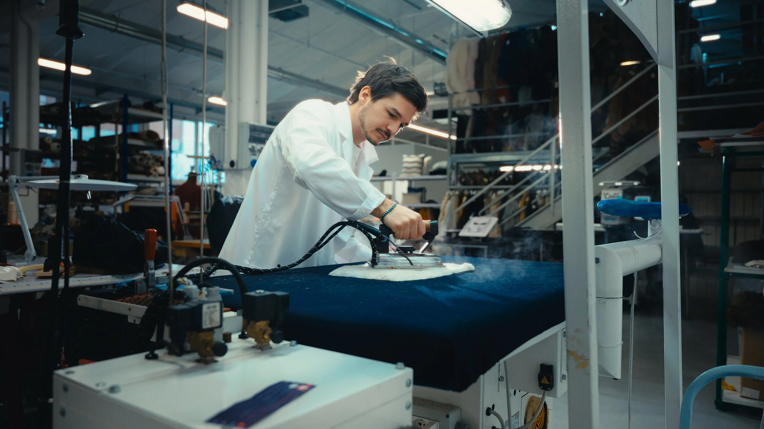 Uomo che lavora su un tessuto con una pressa in un ambiente industriale o laboratorio