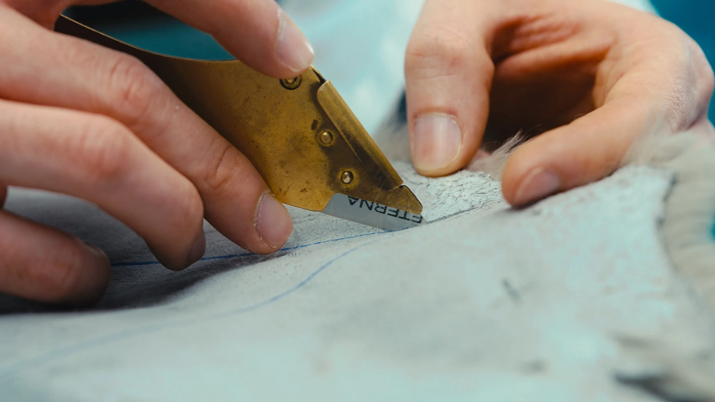 Mani che usano una taglierina per tessuti su un tessuto bianco con linee di taglio