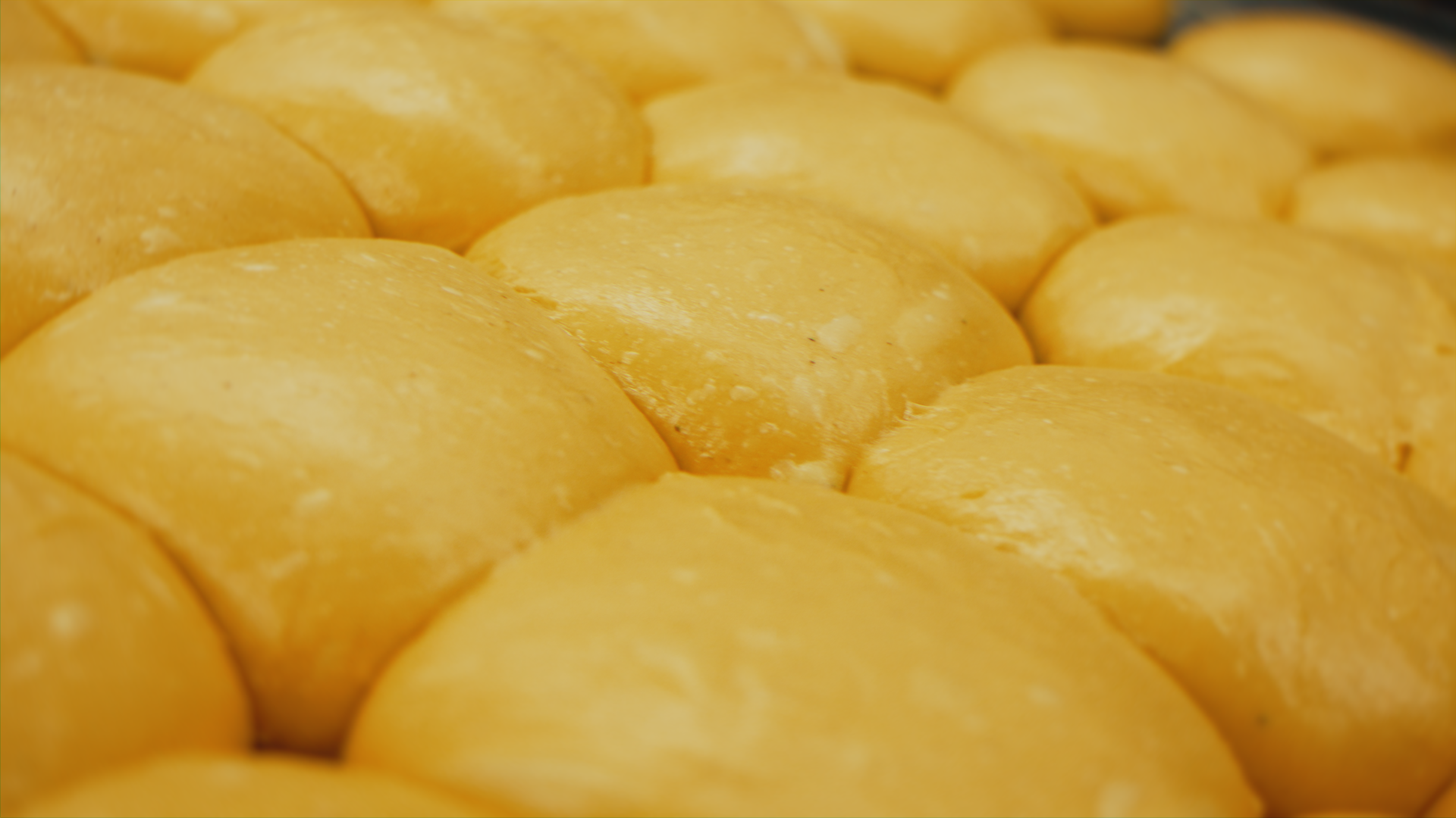 Palline di formaggio giallo, vicine tra loro, con superficie liscia e leggermente lucida.