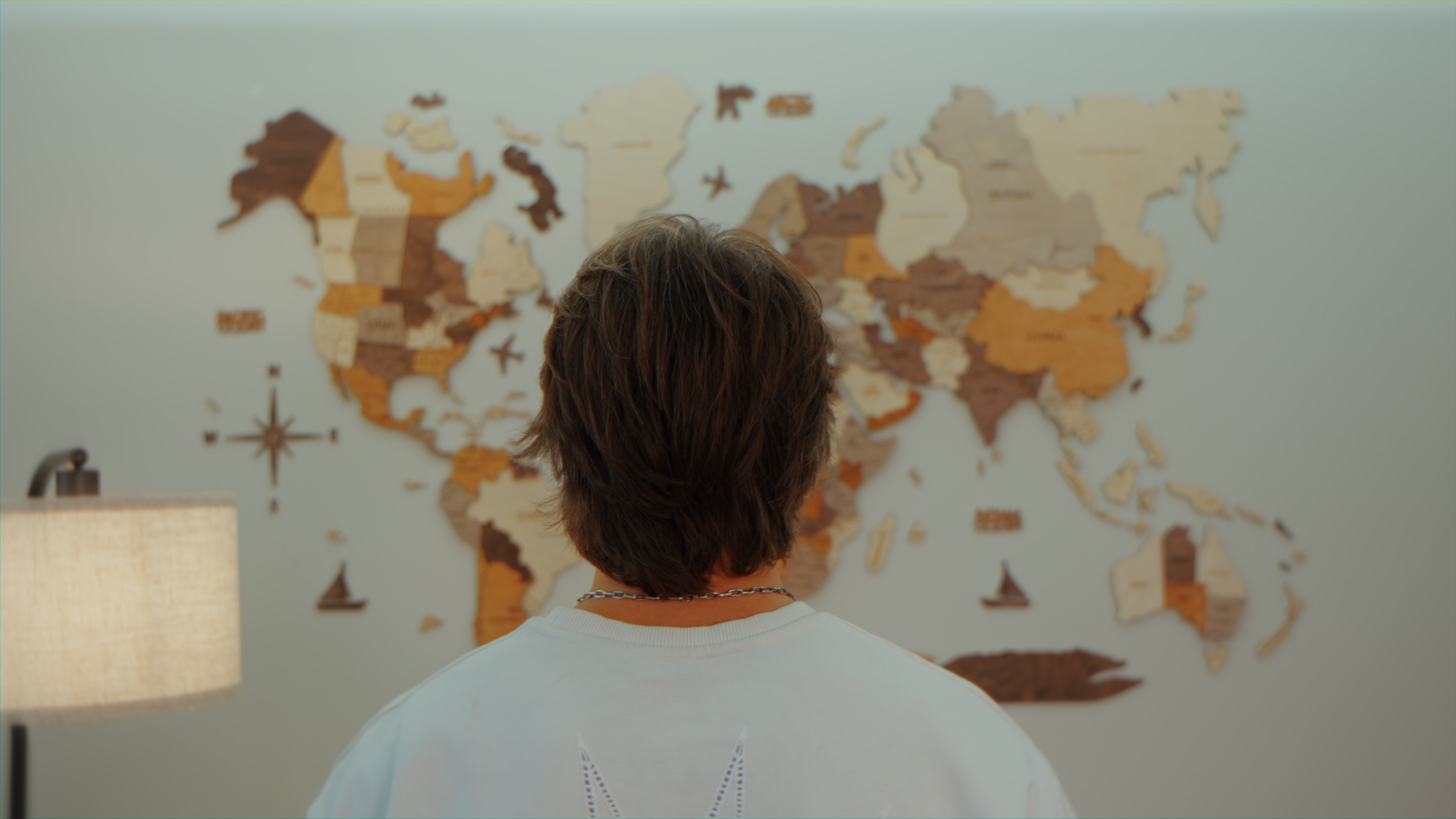 Persona con capelli castani corti che osserva una mappa del mondo su una parete