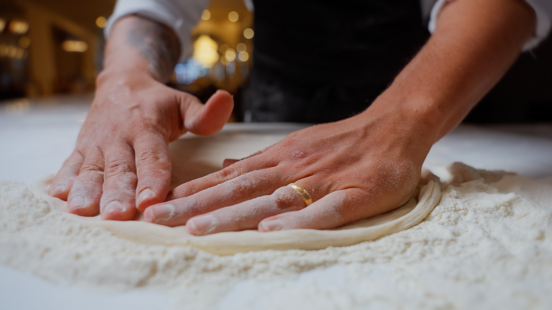Mani che stendono e modellano la pasta fresca sulla superficie infarinata