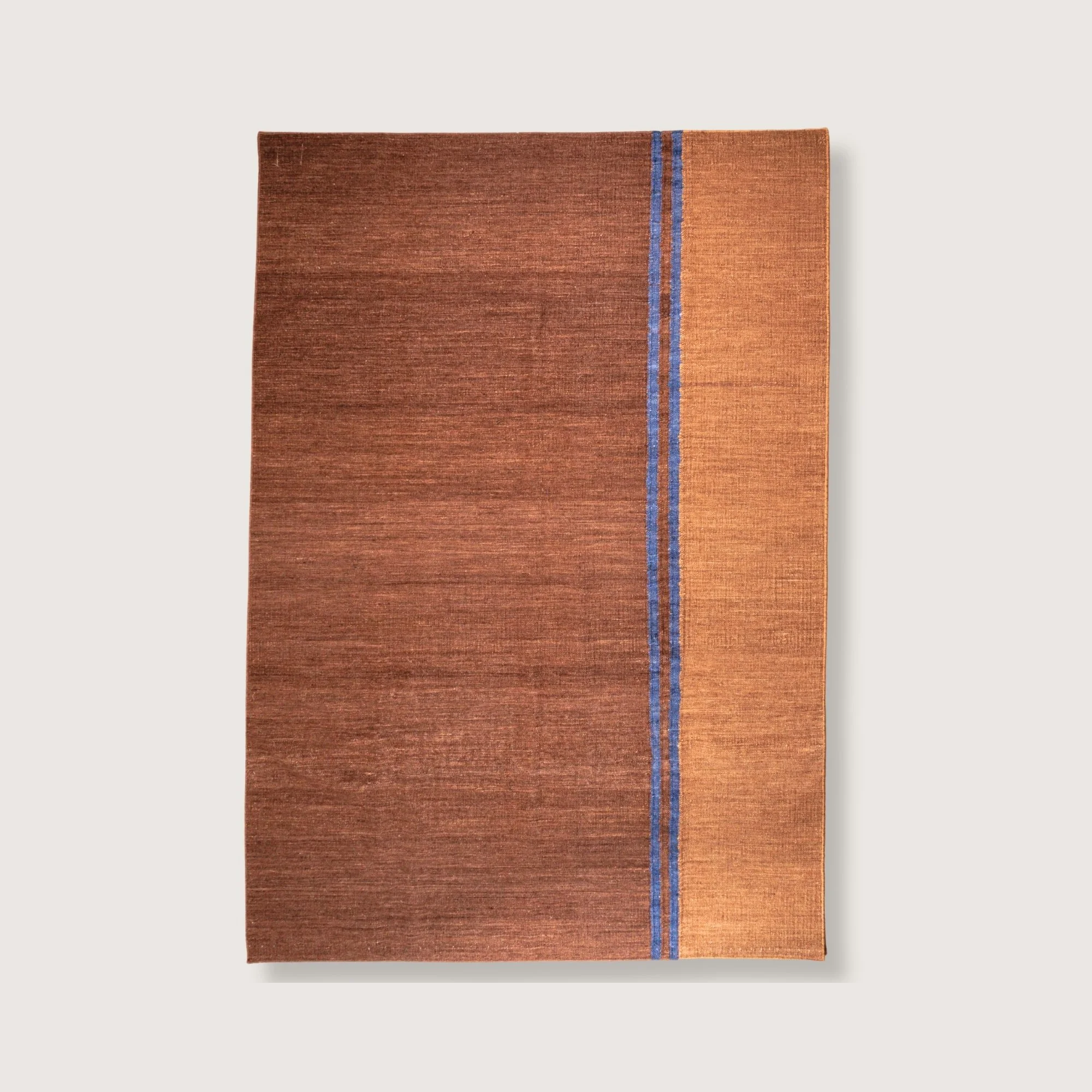 Handwoven rug with earthy tones and a soft pink line. Minimal flatweave design with natural abrash.