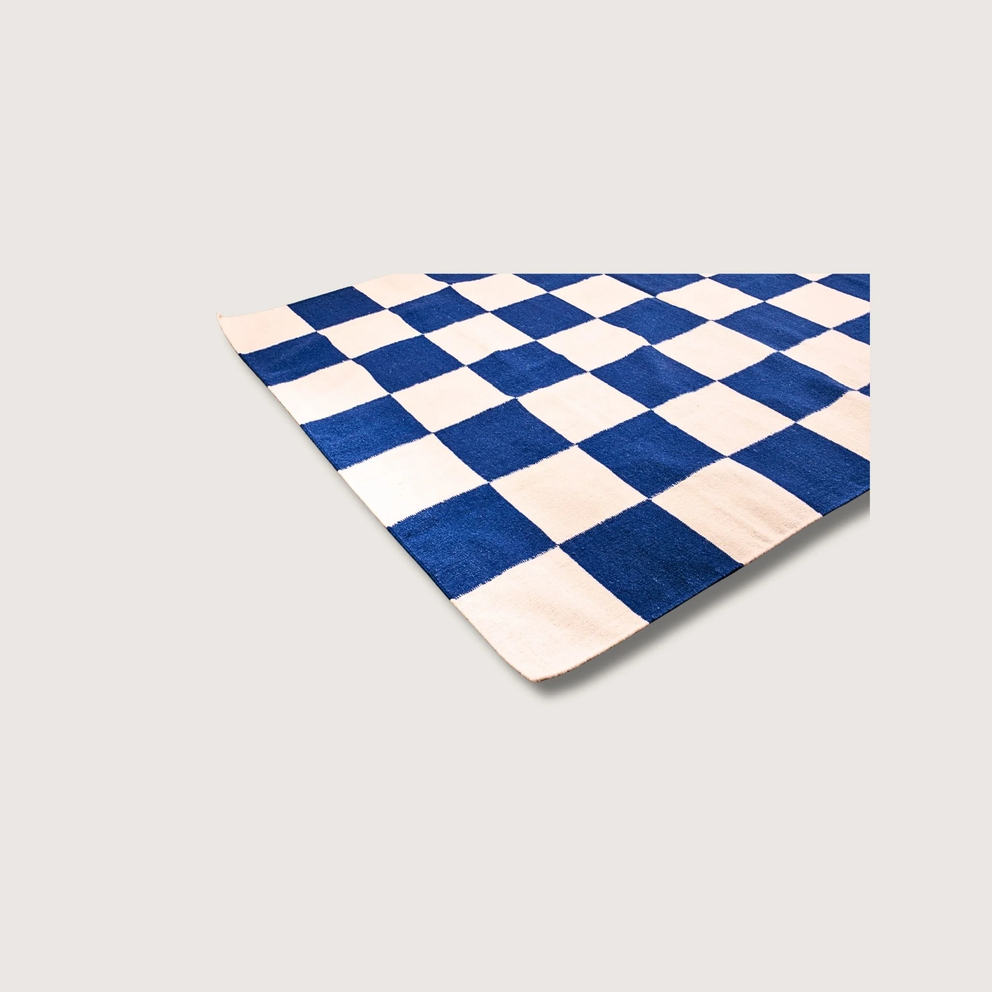 Angled view of Khana Neel rug with blue square detail and natural wool texture