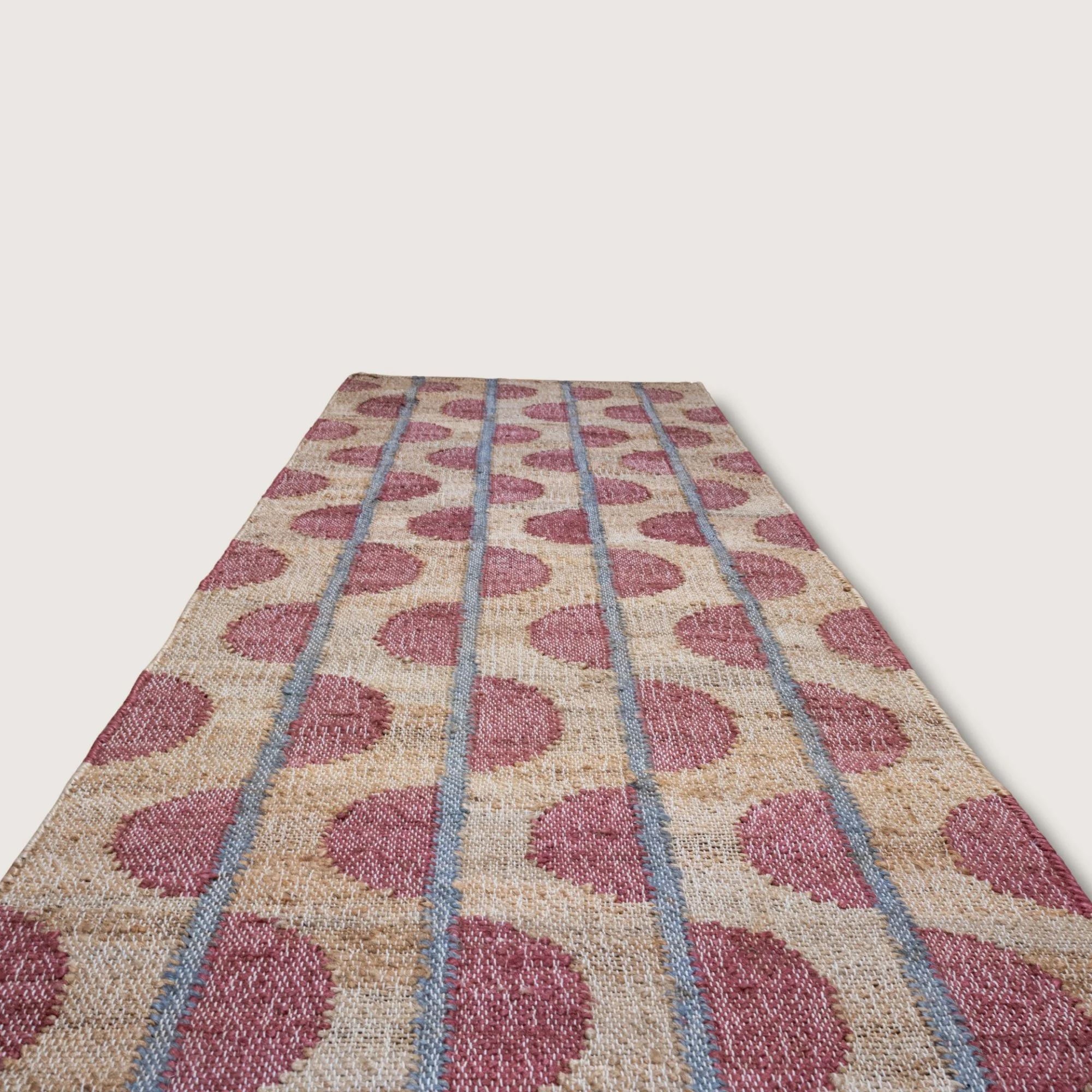 Handwoven jute runner with repeating half-moon pattern in dusty gulabi and natural sand tones.