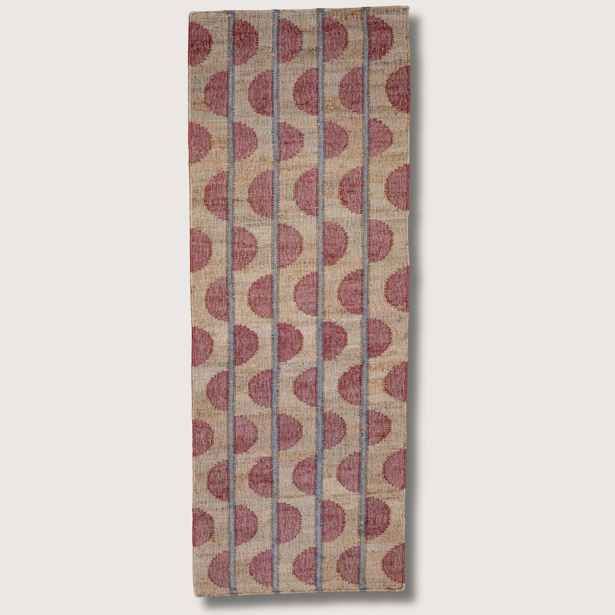 Handwoven jute runner with repeating half-moon pattern in dusty gulabi and natural sand tones.