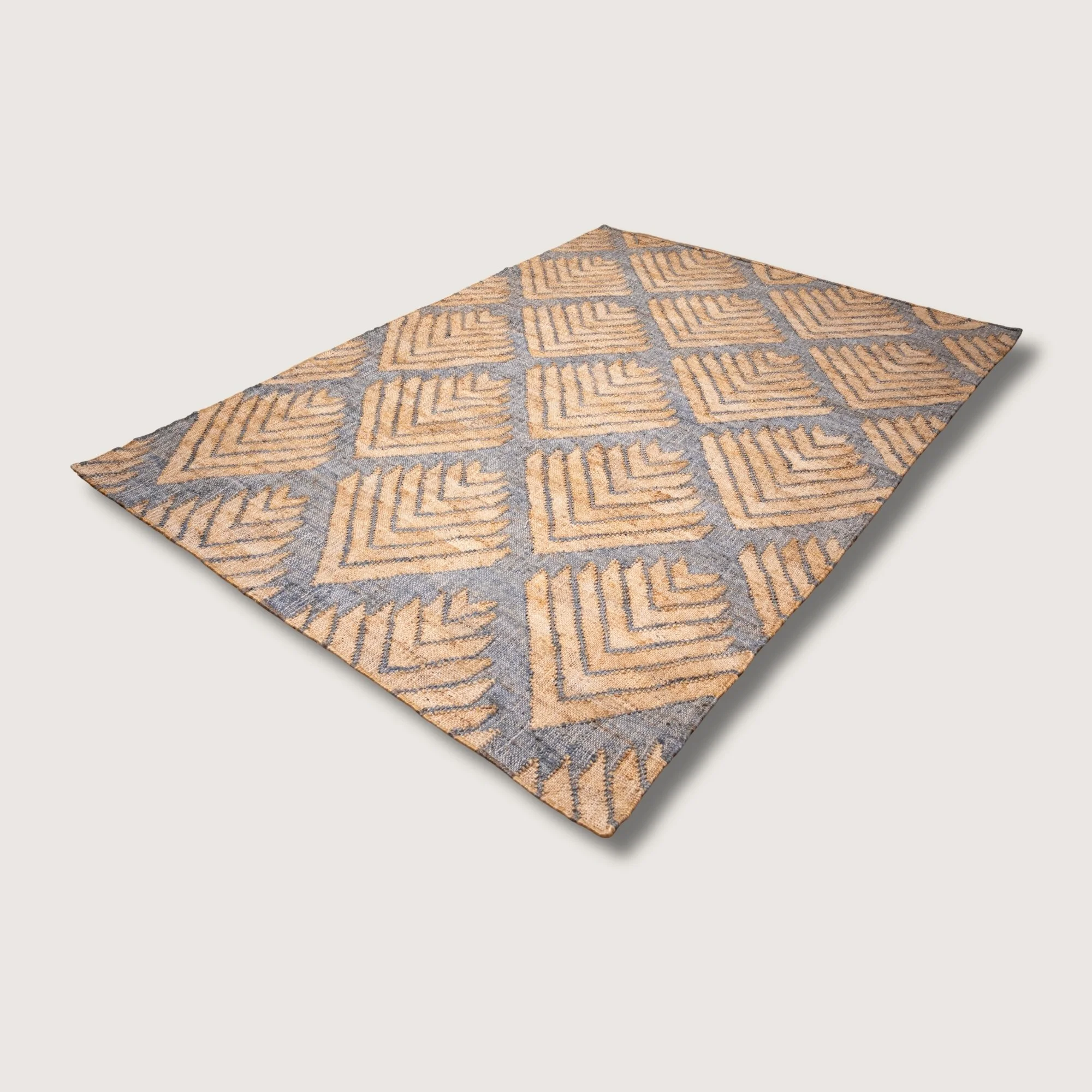 Handwoven jute rug with textured palm-inspired geometric pattern in natural sand and muted blue-grey tones.