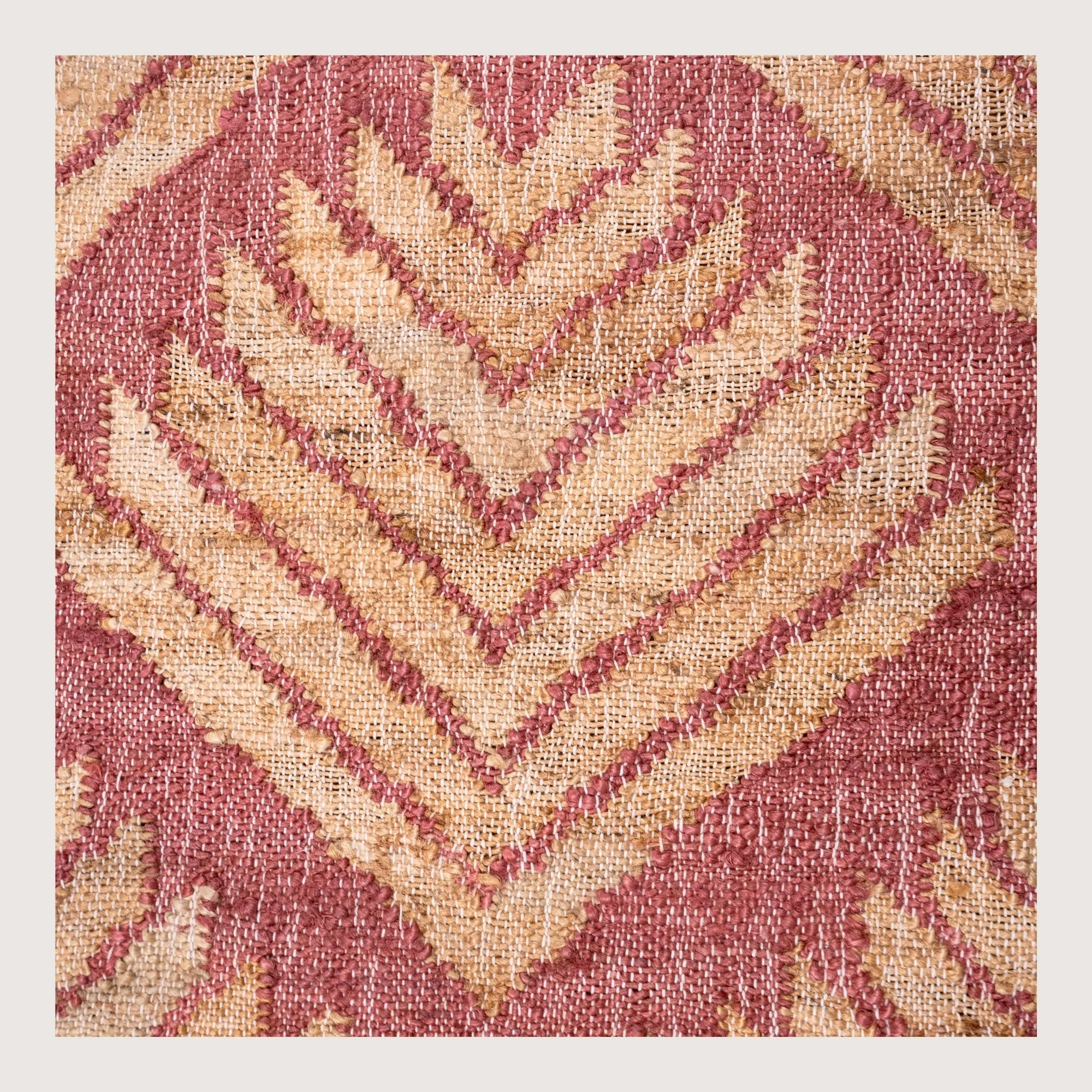 Handwoven jute rug with textured palm-inspired geometric pattern in dusty gulabi and natural sand tones.