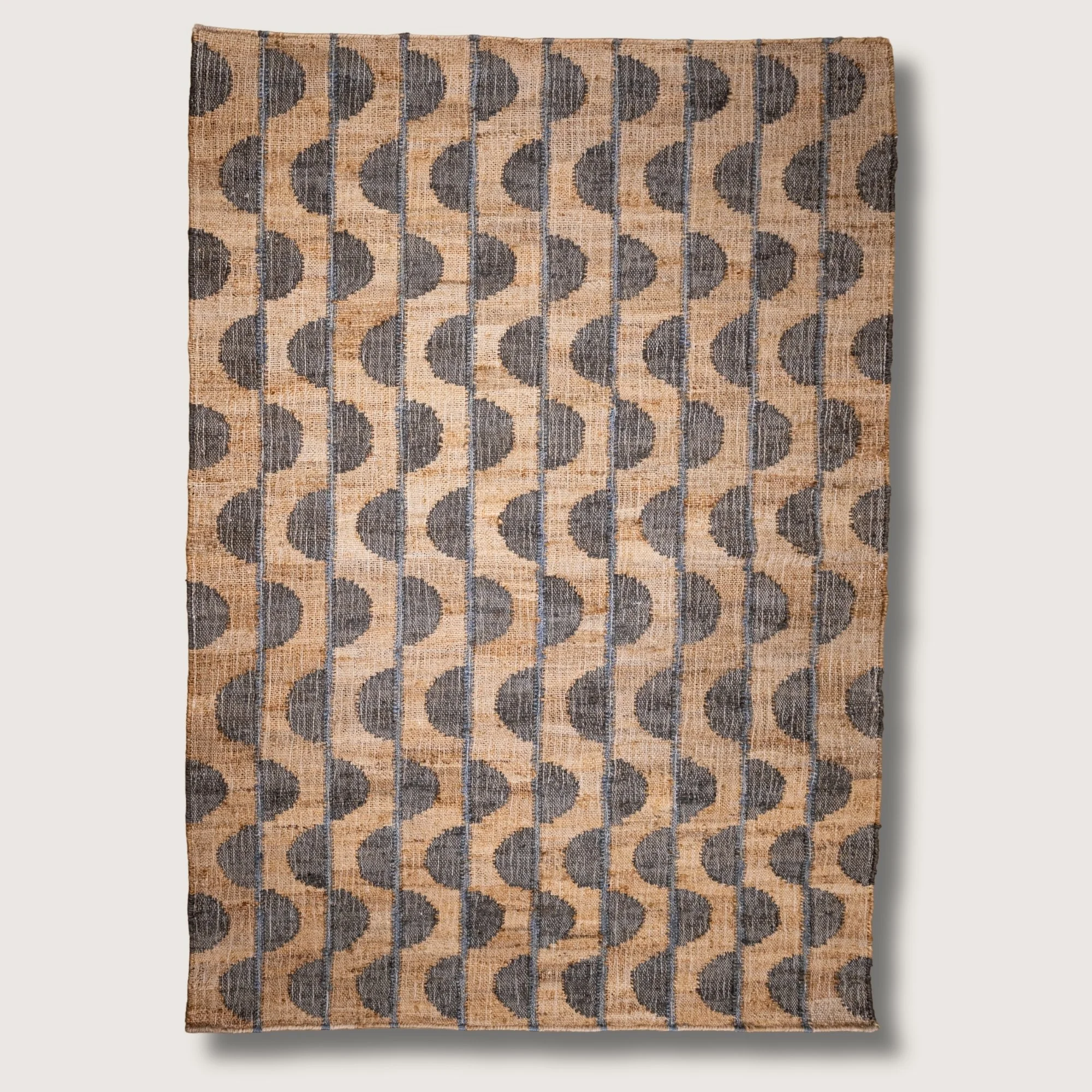 Handwoven jute rug with repeating half-moon pattern in muted zaitun and natural sand tones.