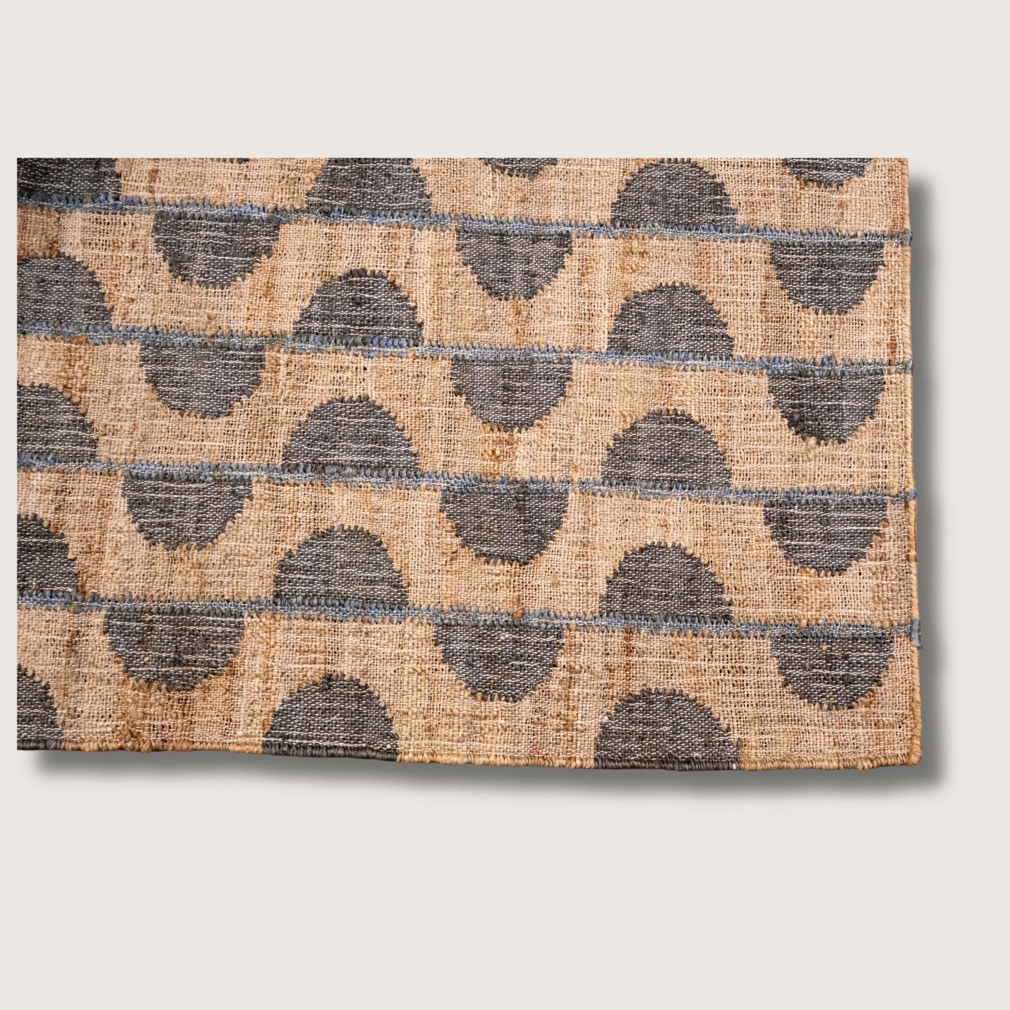 Handwoven jute rug with repeating half-moon pattern in muted zaitun and natural sand tones.