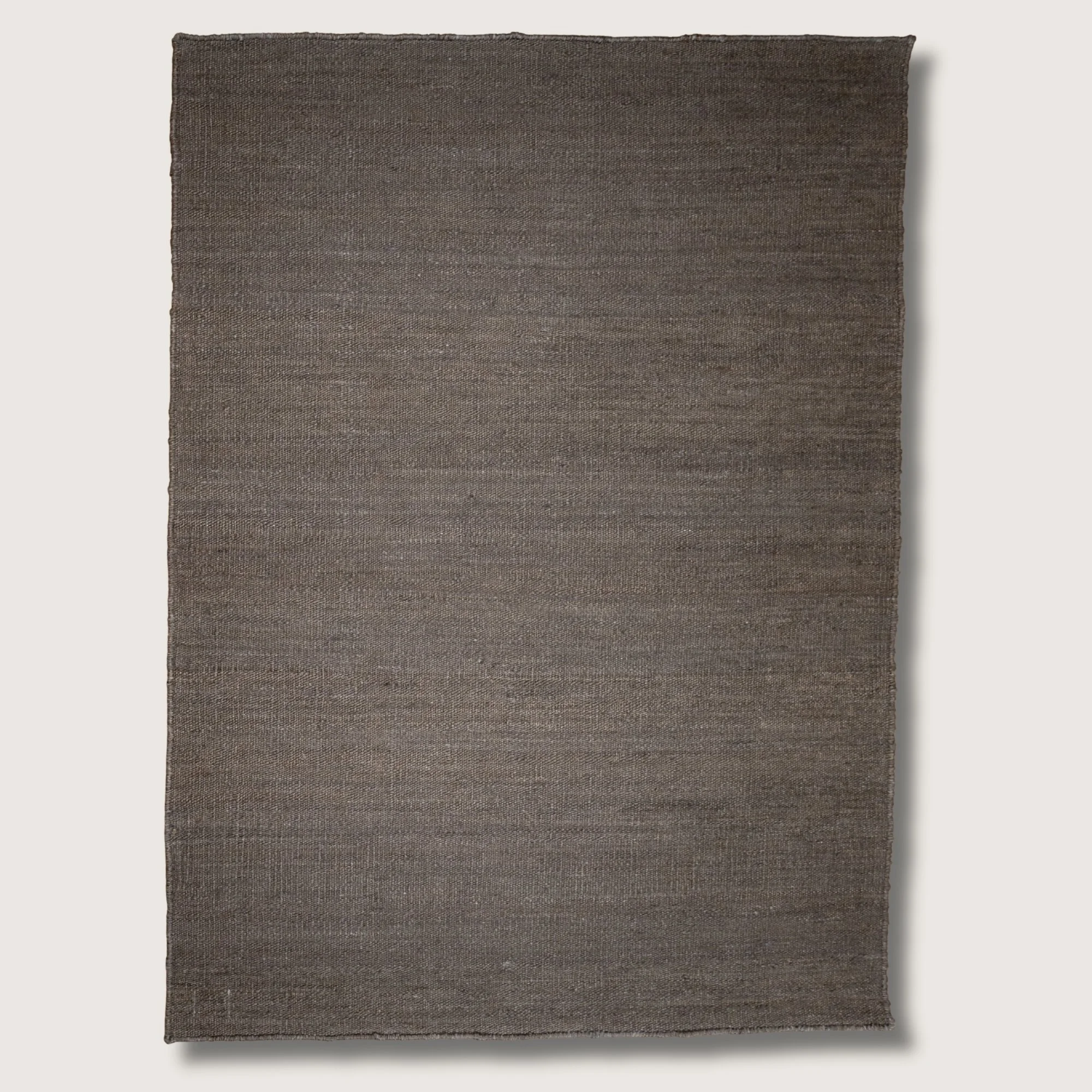 Plain handwoven jute rug in muted zaitun tones with subtle natural texture.