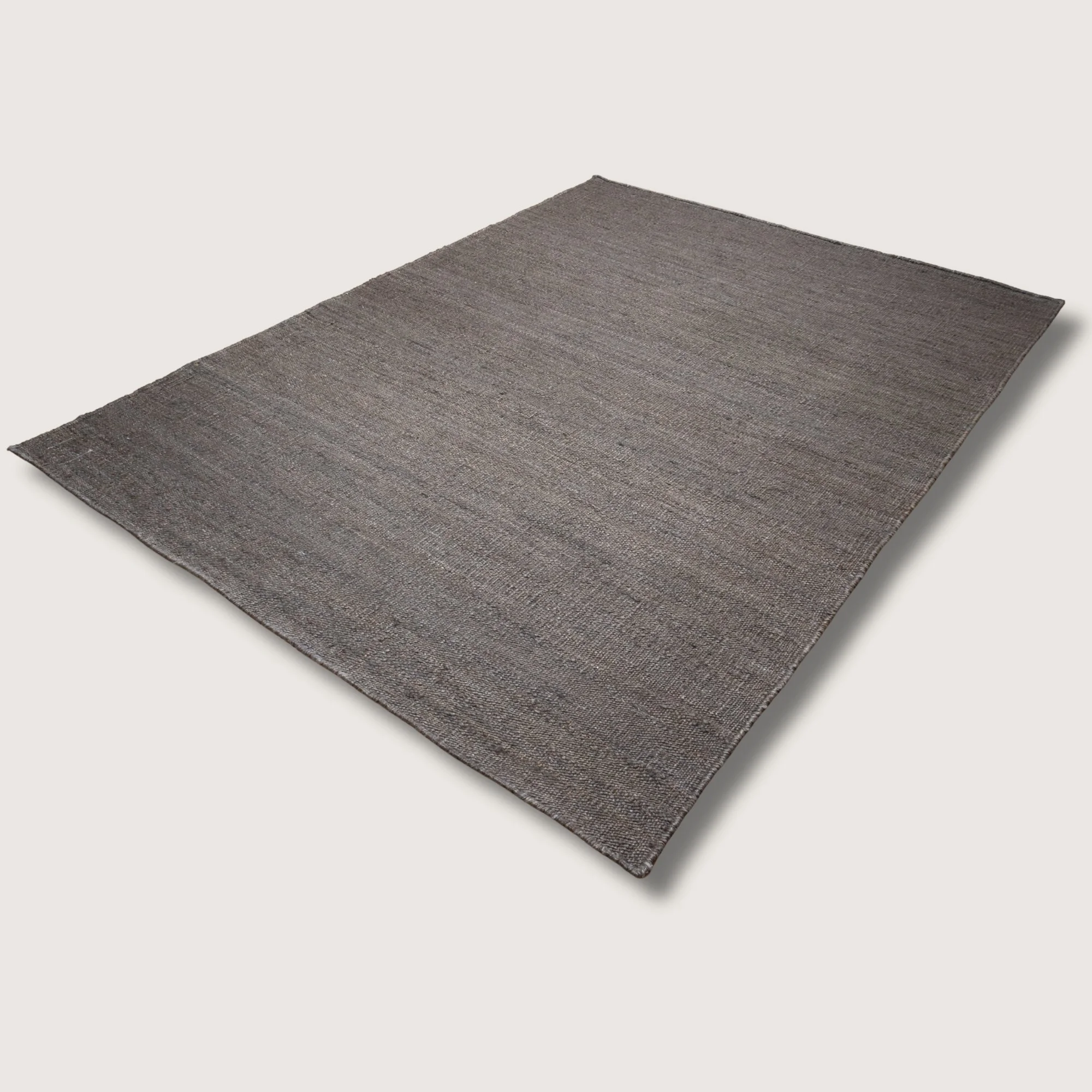 Plain handwoven jute rug in muted zaitun tones with subtle natural texture.