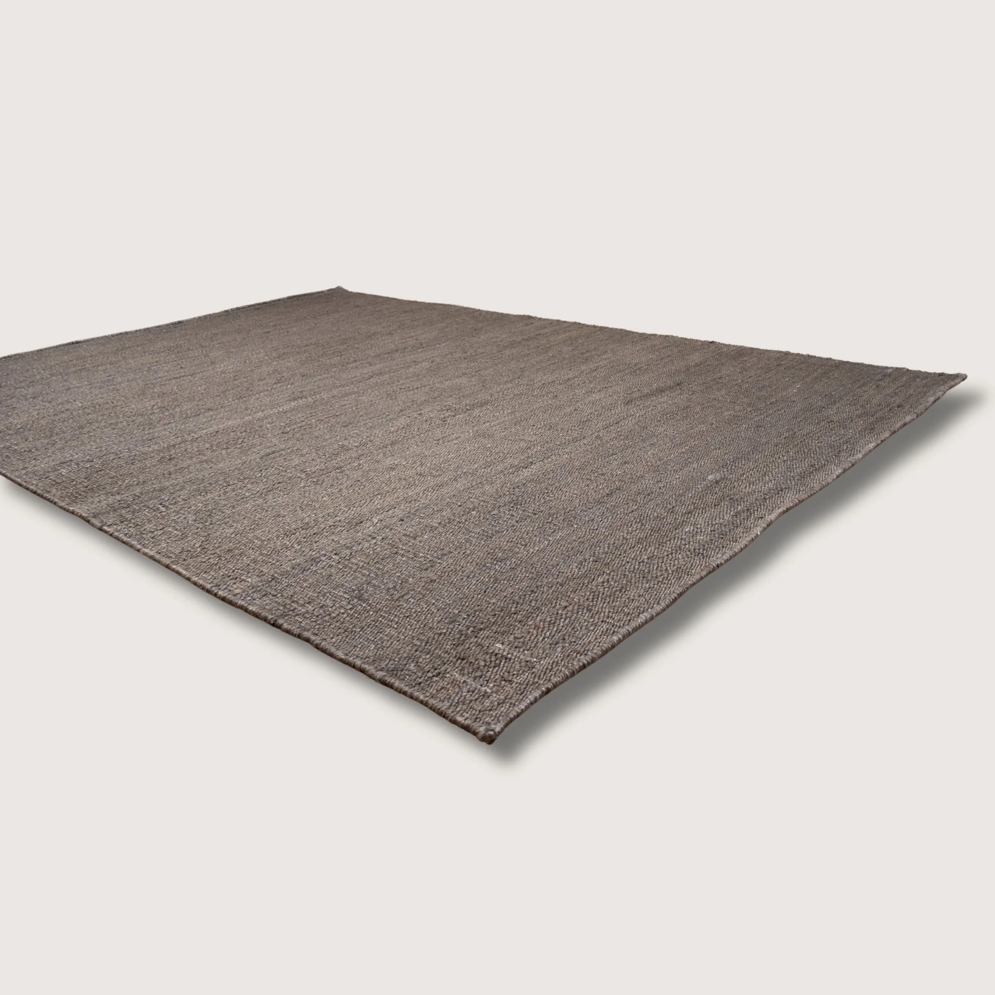 Plain handwoven jute rug in muted zaitun tones with subtle natural texture.
