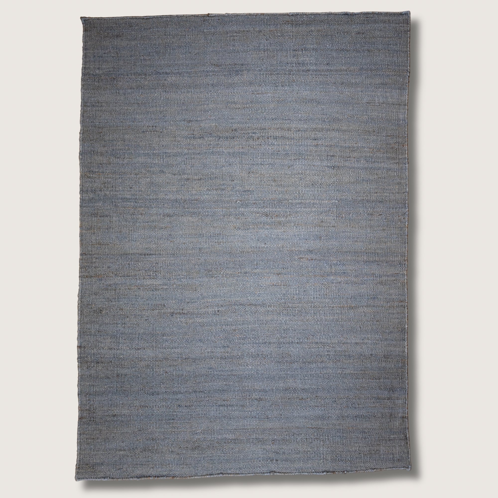 Plain handwoven jute rug in muted neel tones with subtle natural texture.