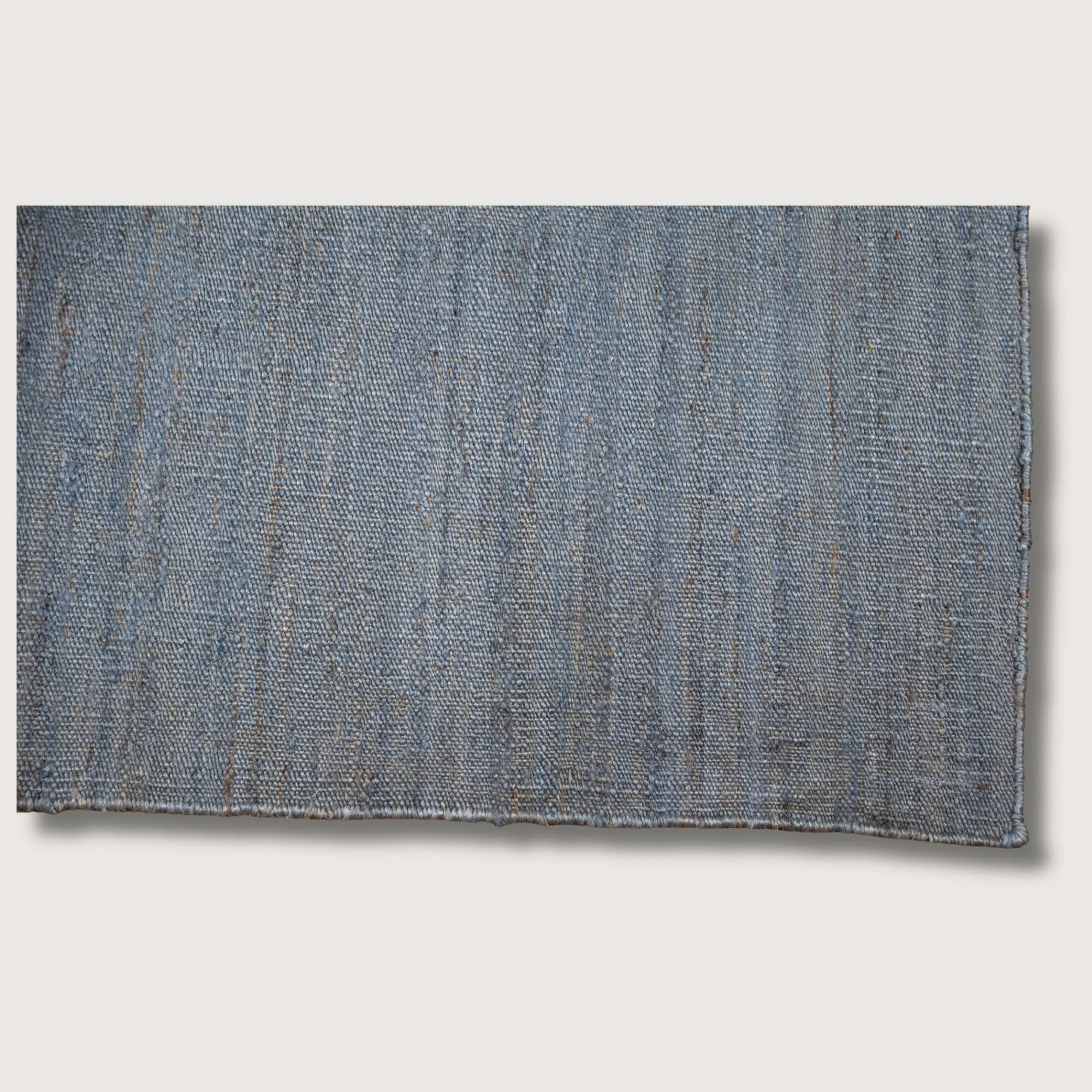 Plain handwoven jute rug in muted neel tones with subtle natural texture.