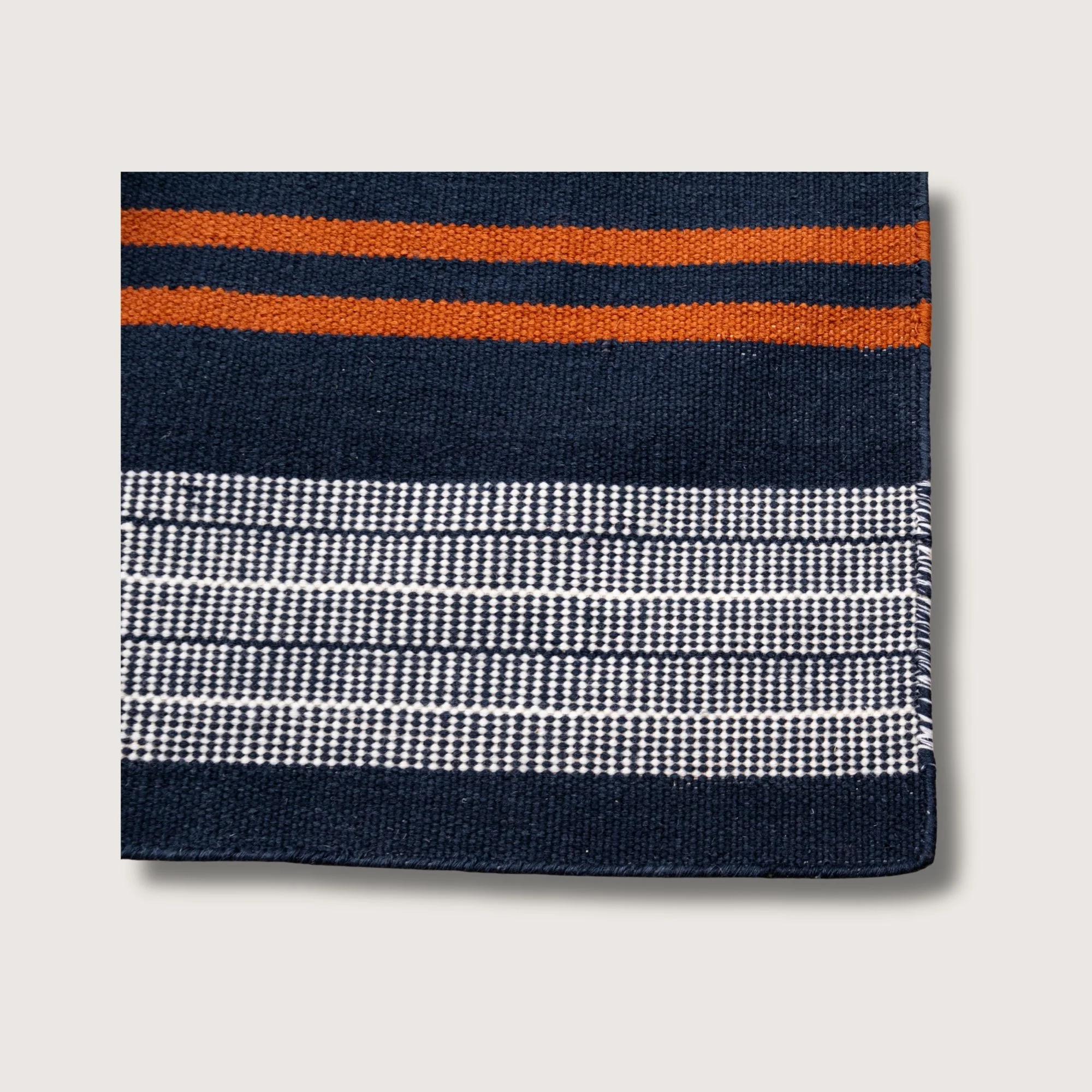 Handwoven wool flatweave rug with striped pattern in deep neel, whisper white, and Bombay brown tones.