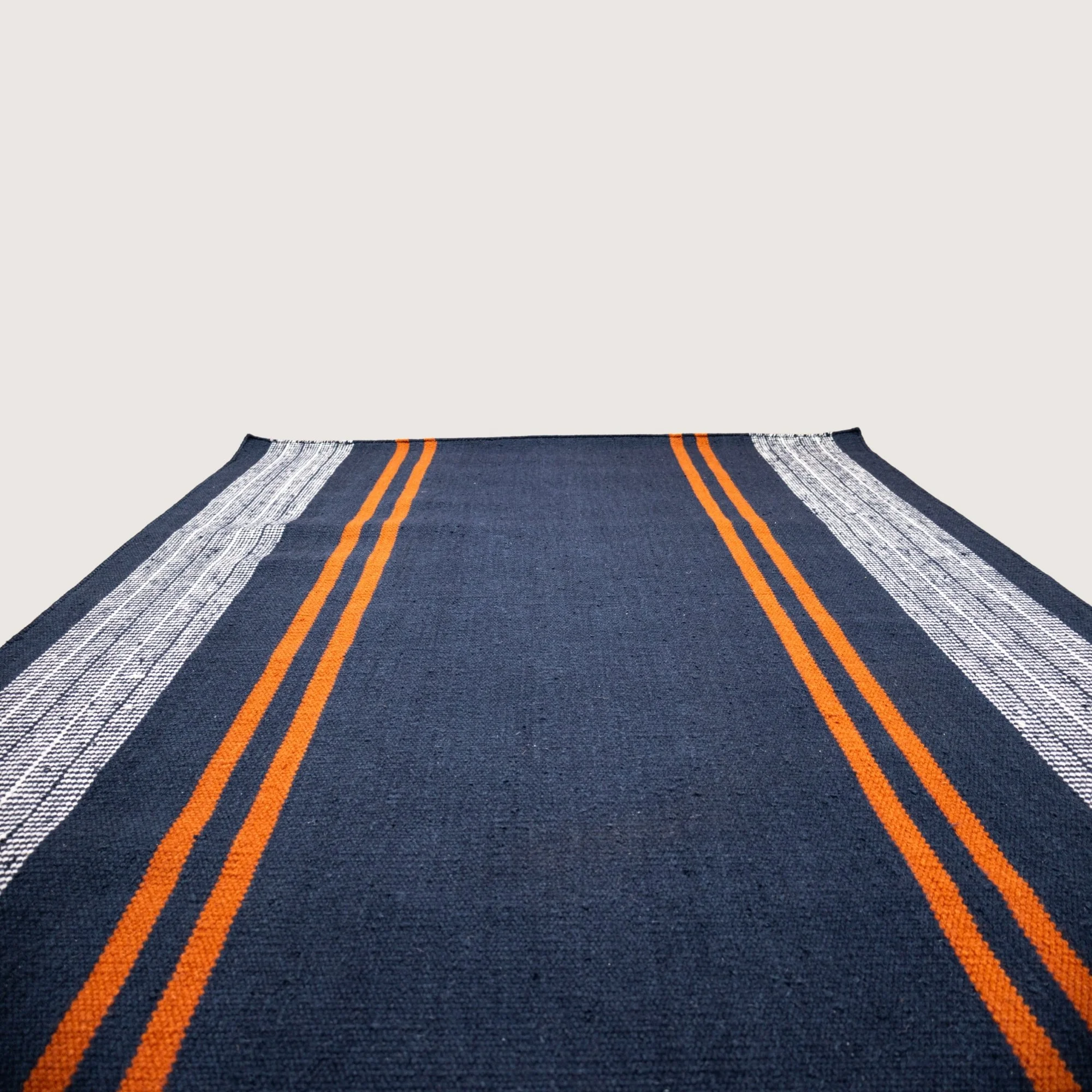 Handwoven wool flatweave rug with striped pattern in deep neel, whisper white, and Bombay brown tones.