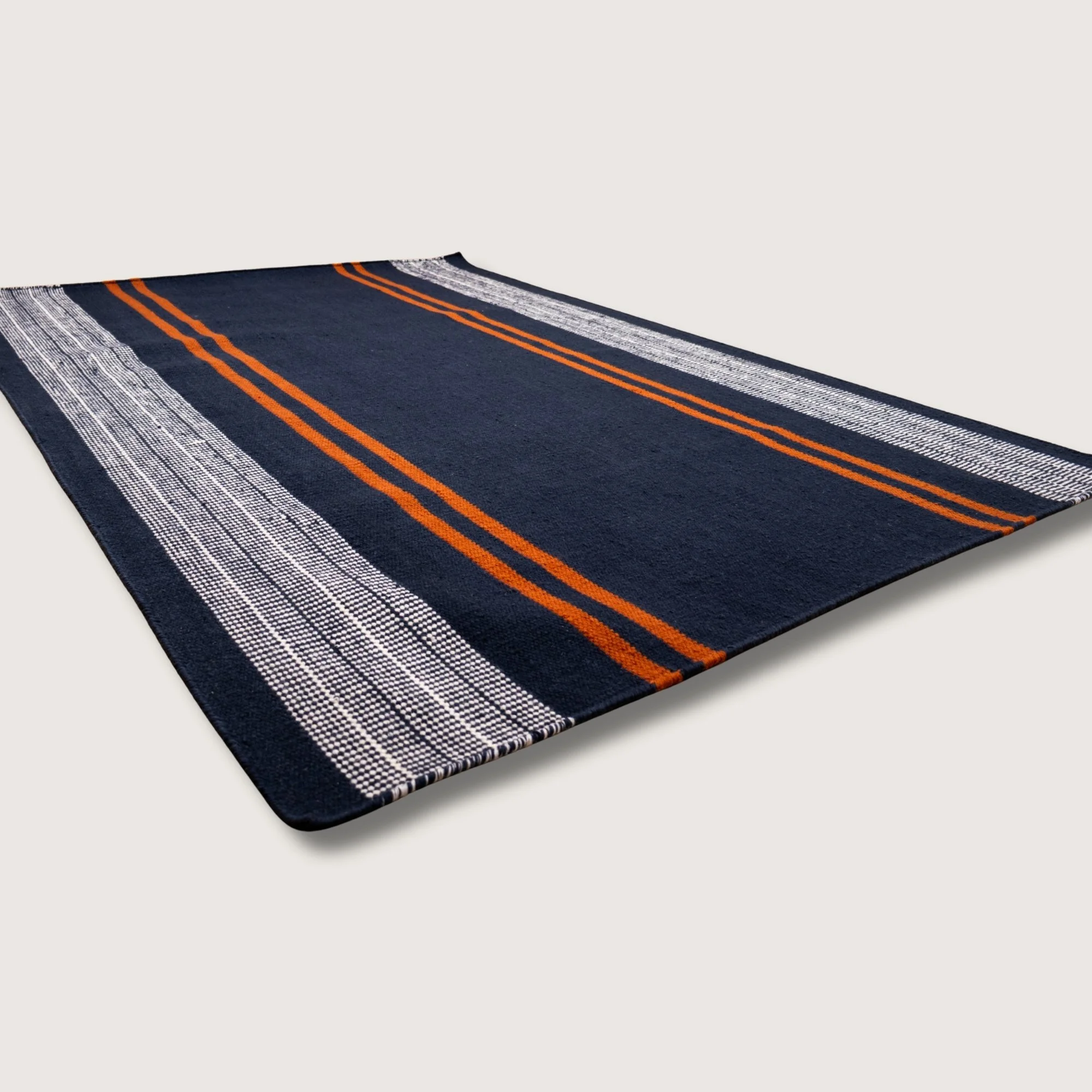 Handwoven wool flatweave rug with striped pattern in deep neel, whisper white, and Bombay brown tones.