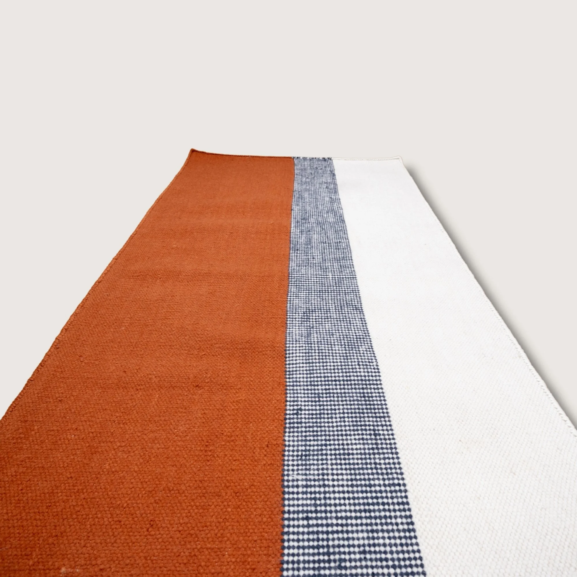 Handwoven wool flatweave runner with color block design in Bombay, deep neel, and whisper white tones.