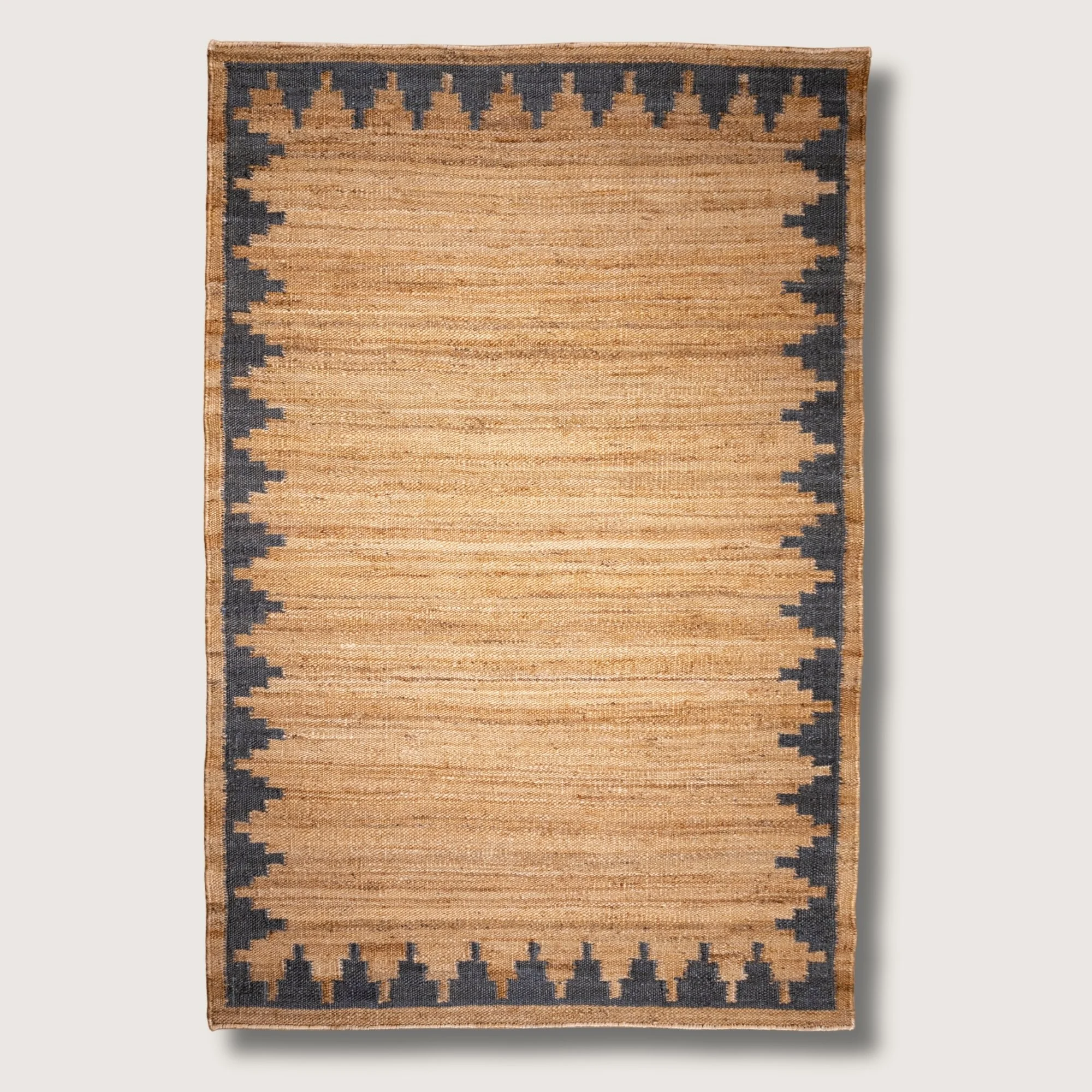 Handwoven jute rug with stepped geometric border in muted zaitun and natural sand tones.