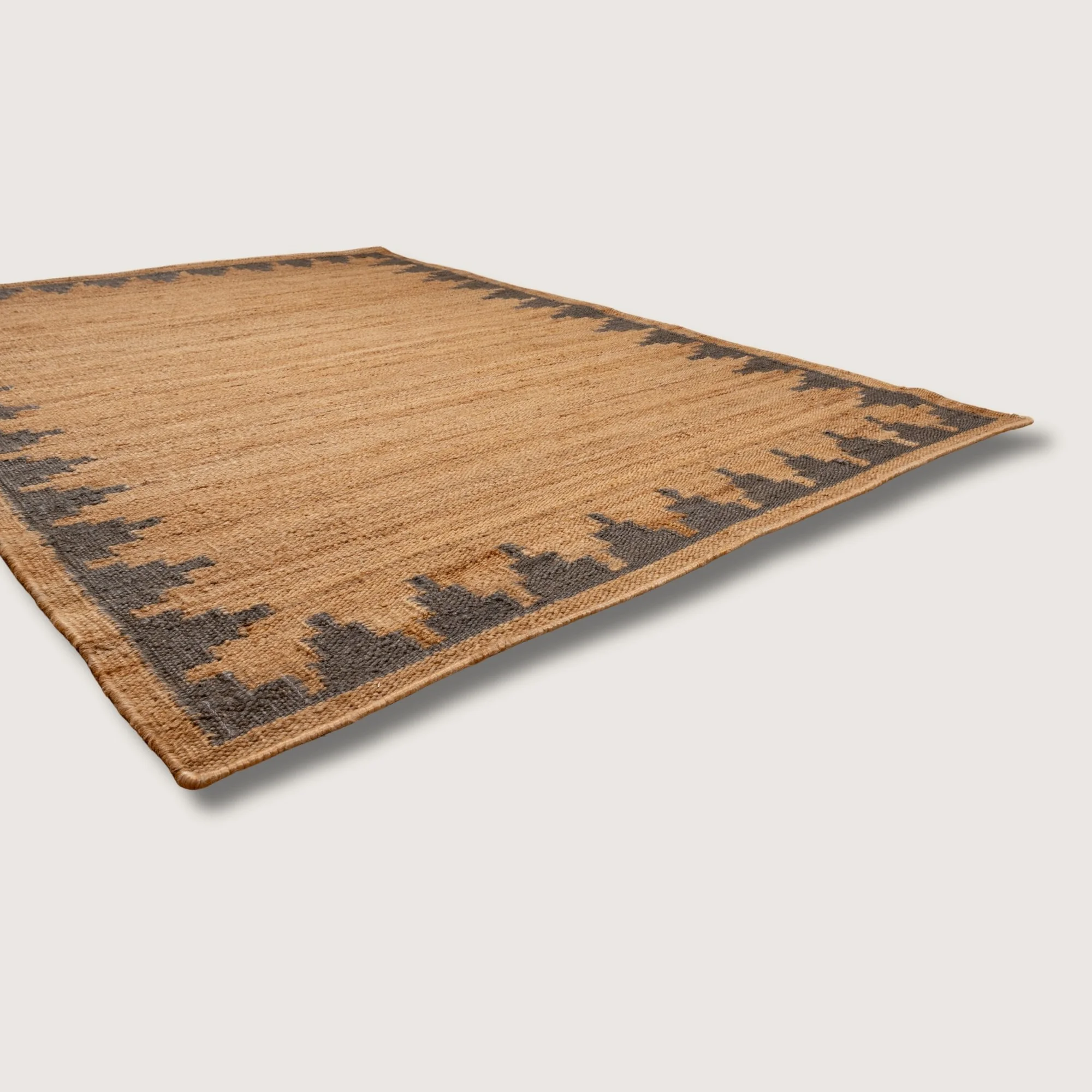 Handwoven jute rug with stepped geometric border in muted zaitun and natural sand tones.