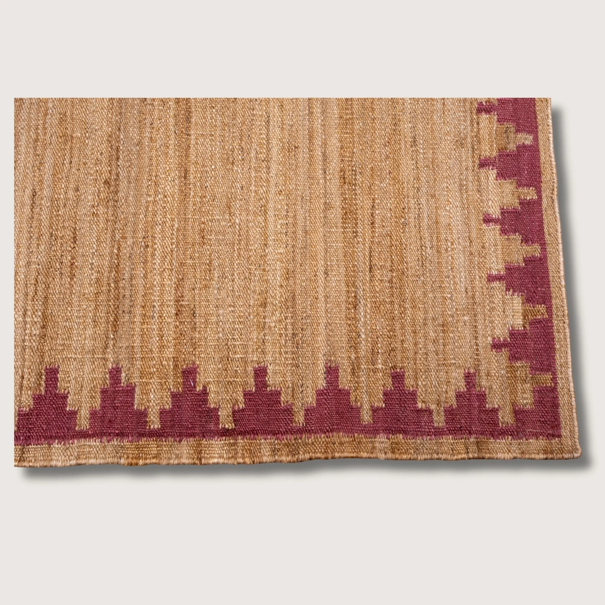 Handwoven jute rug with stepped geometric border in dusty gulabi and natural sand tones.
