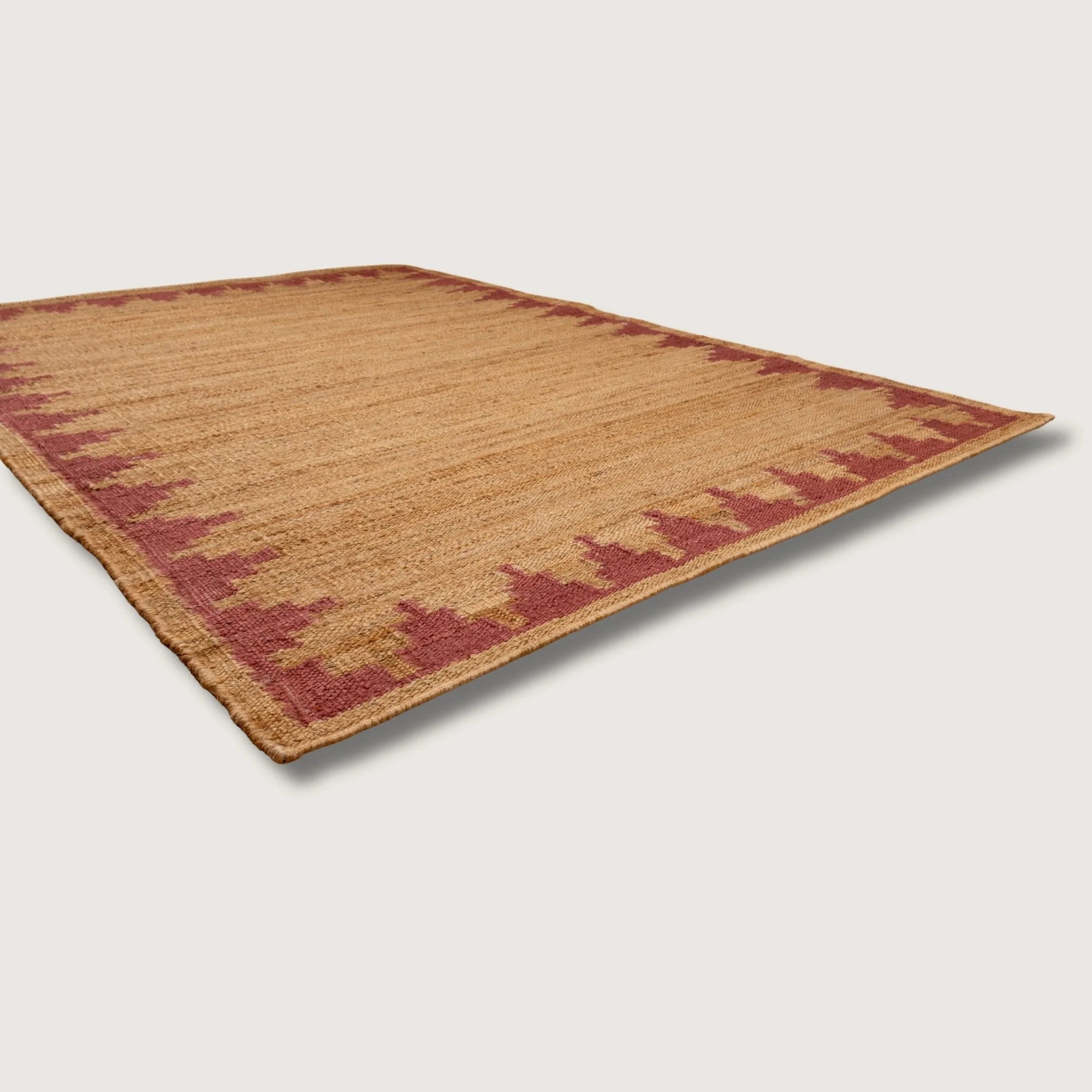 Handwoven jute rug with stepped geometric border in dusty gulabi and natural sand tones.