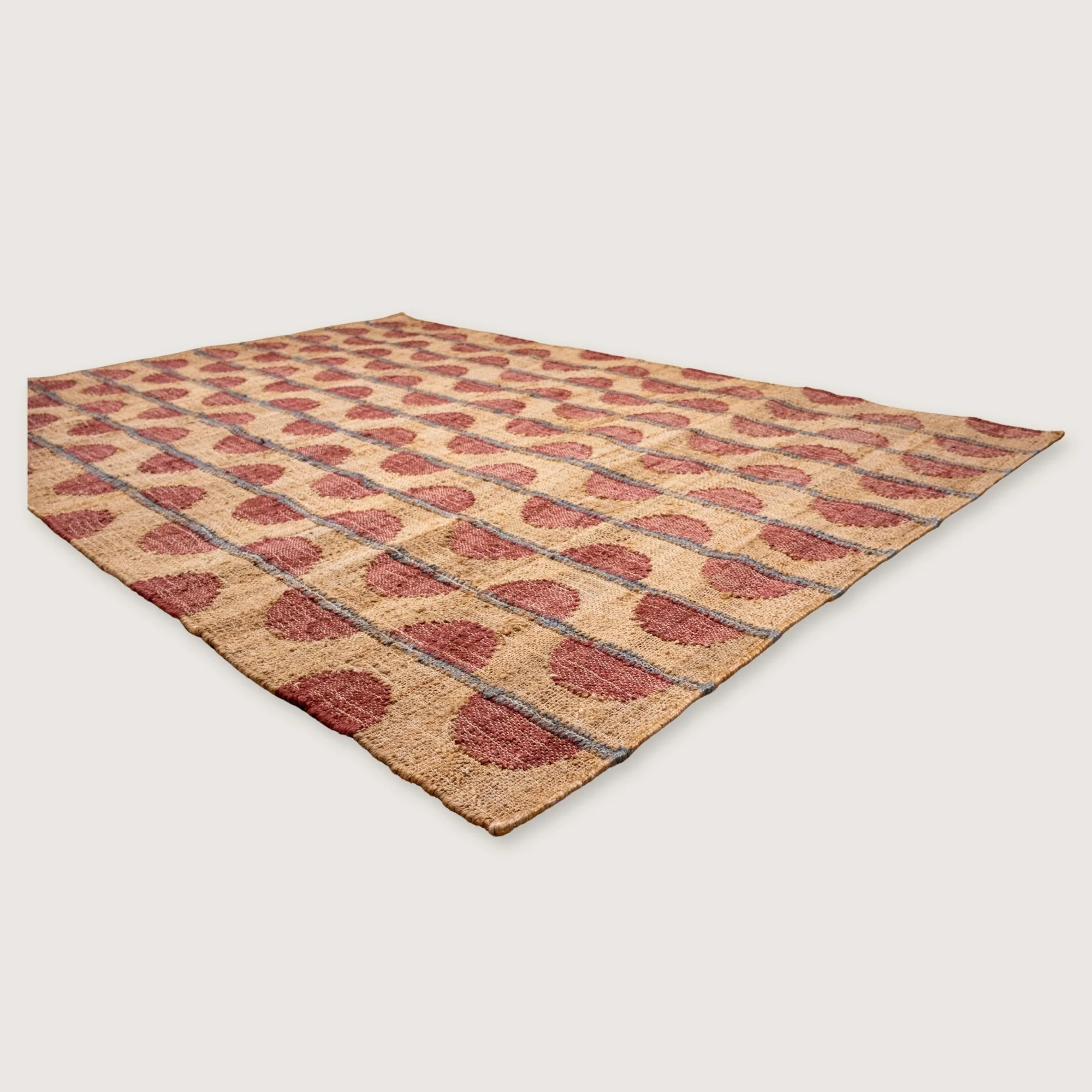 Handwoven jute rug with repeating half-moon pattern in dusty rose and natural sand tones.