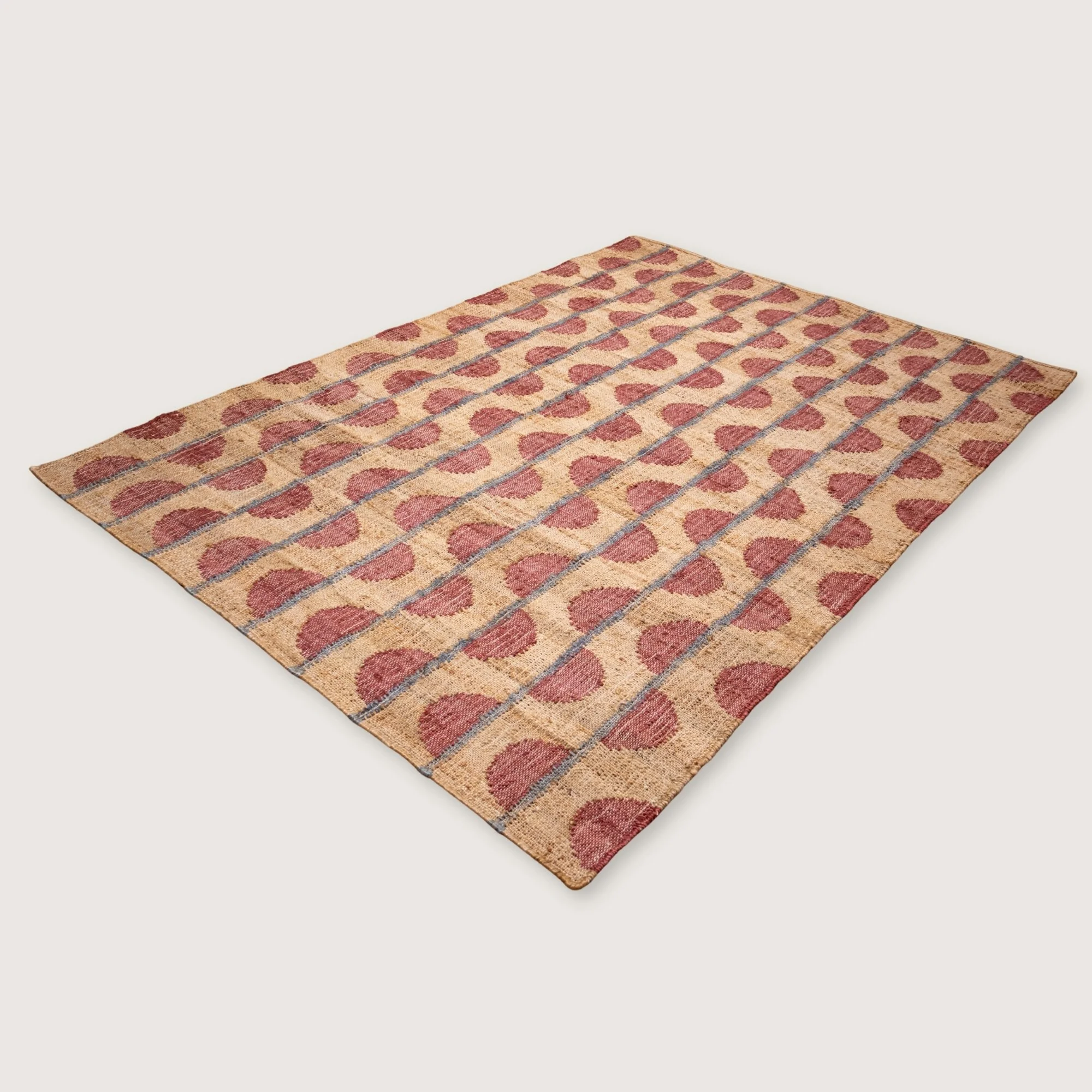 Handwoven jute rug with repeating half-moon pattern in dusty rose and natural sand tones.