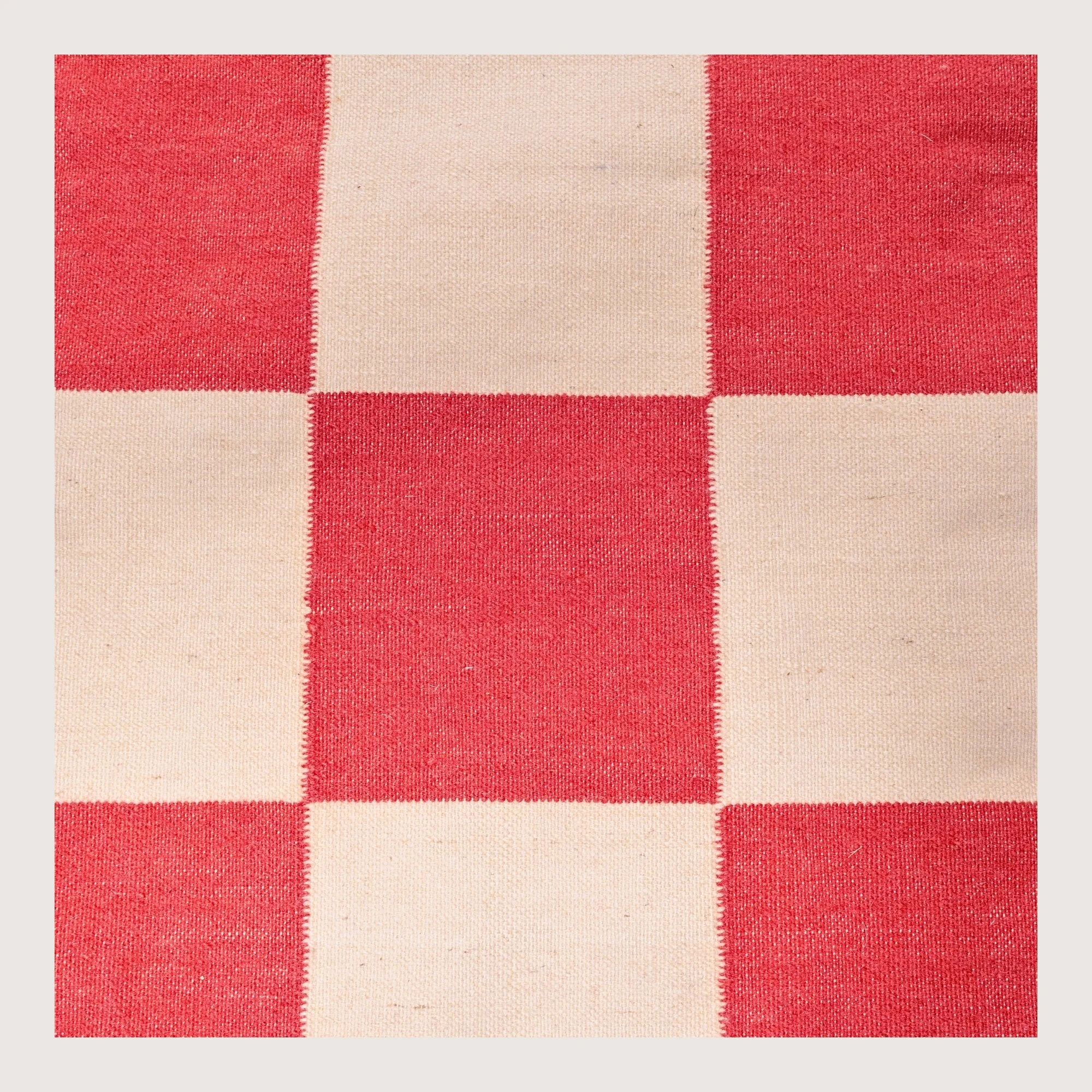 Handwoven wool flatweave rug with checkerboard pattern in red and natural tones