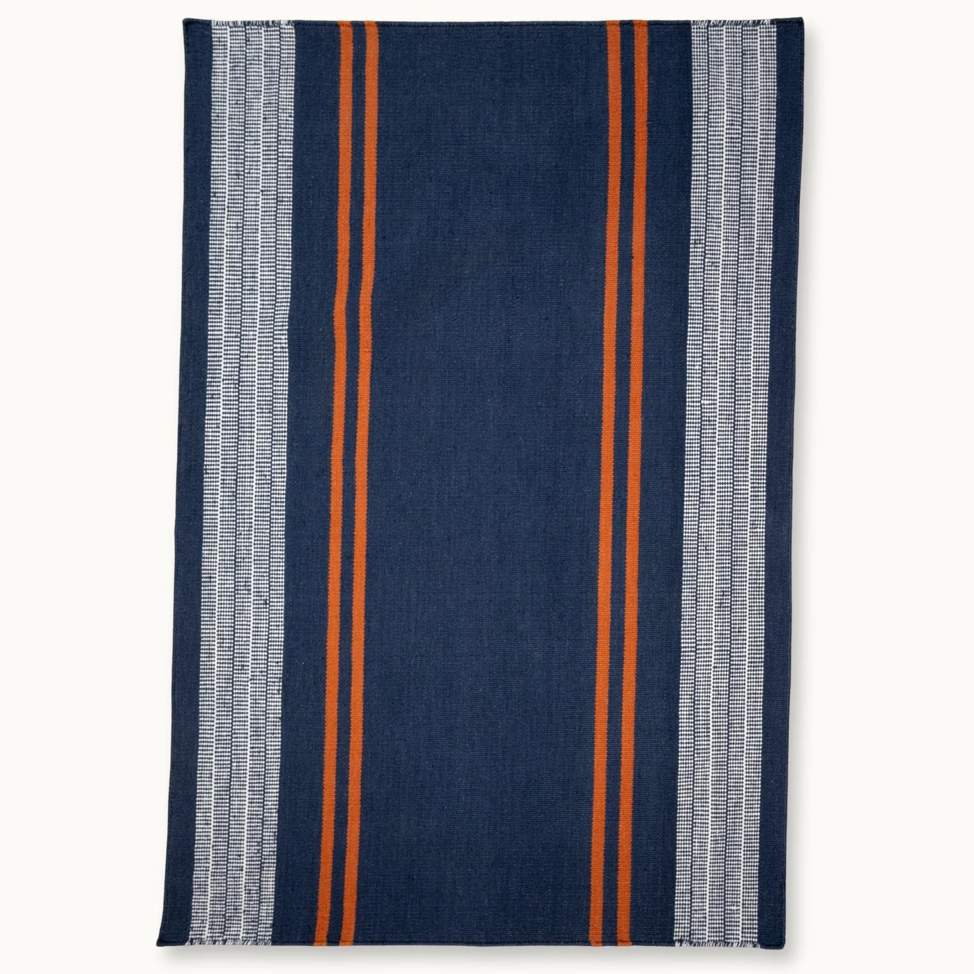 Handwoven wool flatweave rug with striped pattern in deep blue, whisper white, and Bombay brown tones.