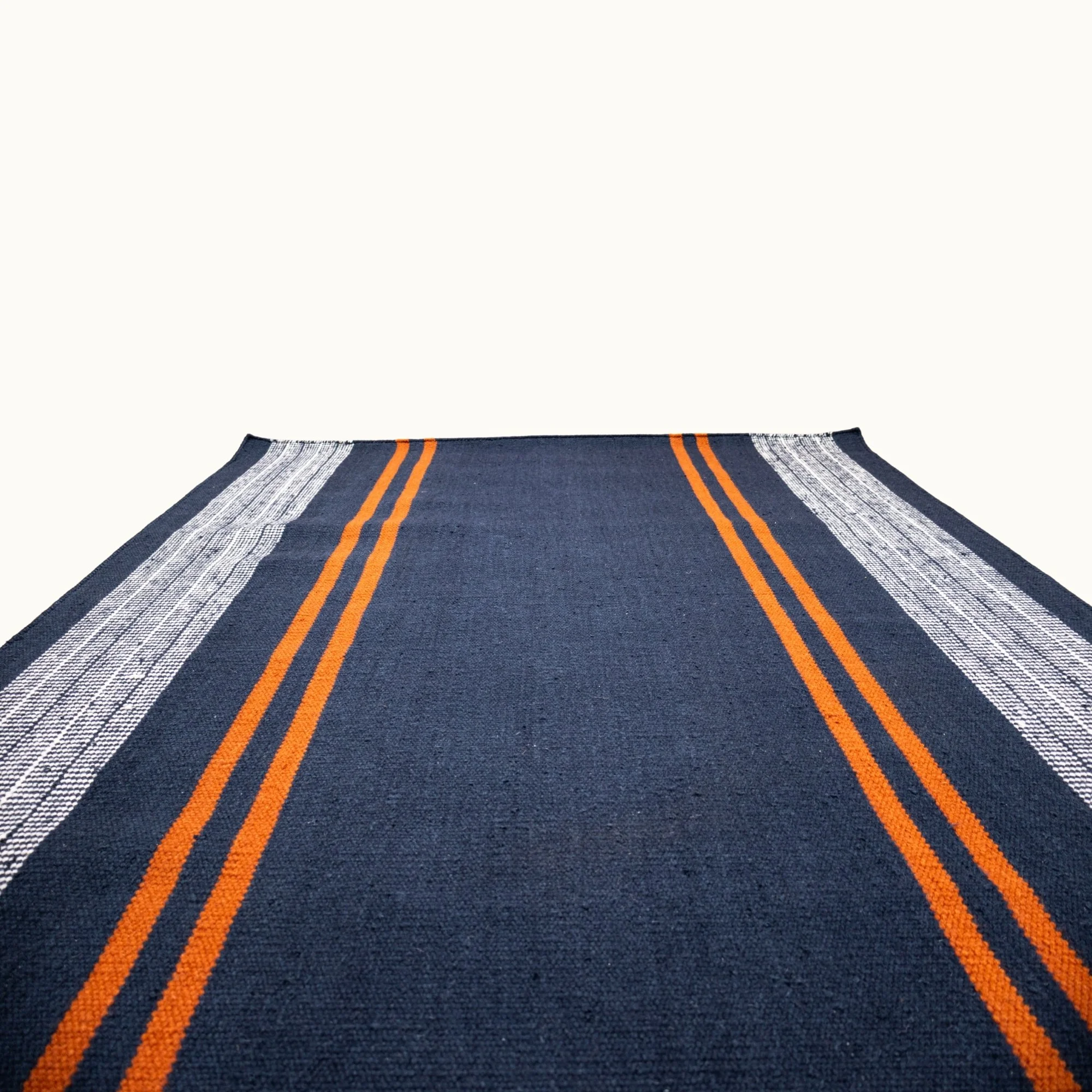 Handwoven wool flatweave rug with striped pattern in deep blue, whisper white, and Bombay brown tones.
