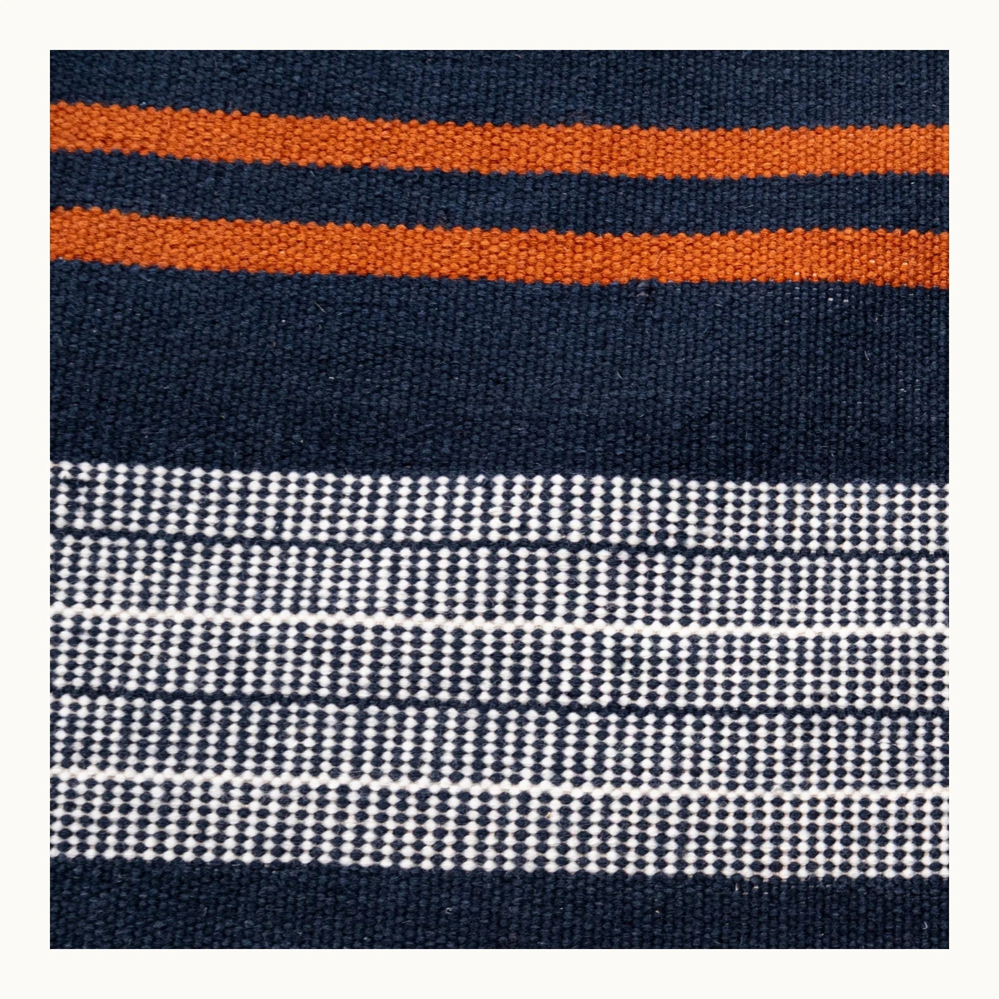 Handwoven wool flatweave rug with striped pattern in deep blue, whisper white, and Bombay brown tones.