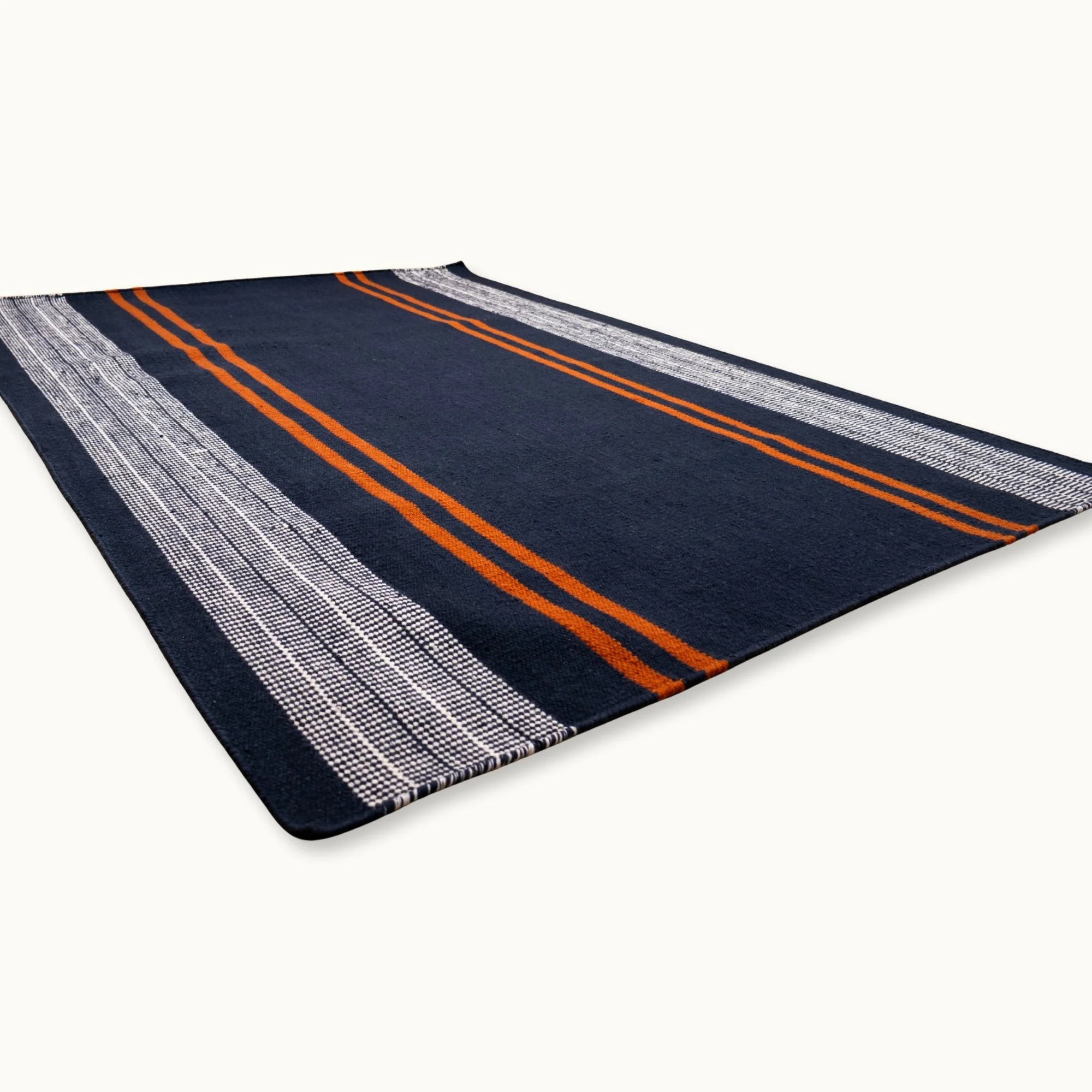 Handwoven wool flatweave rug with striped pattern in deep blue, whisper white, and Bombay brown tones.