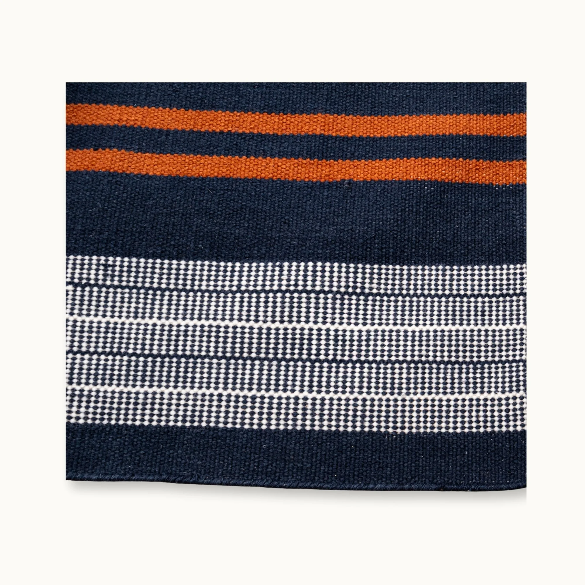 Handwoven wool flatweave rug with striped pattern in deep blue, whisper white, and Bombay brown tones.