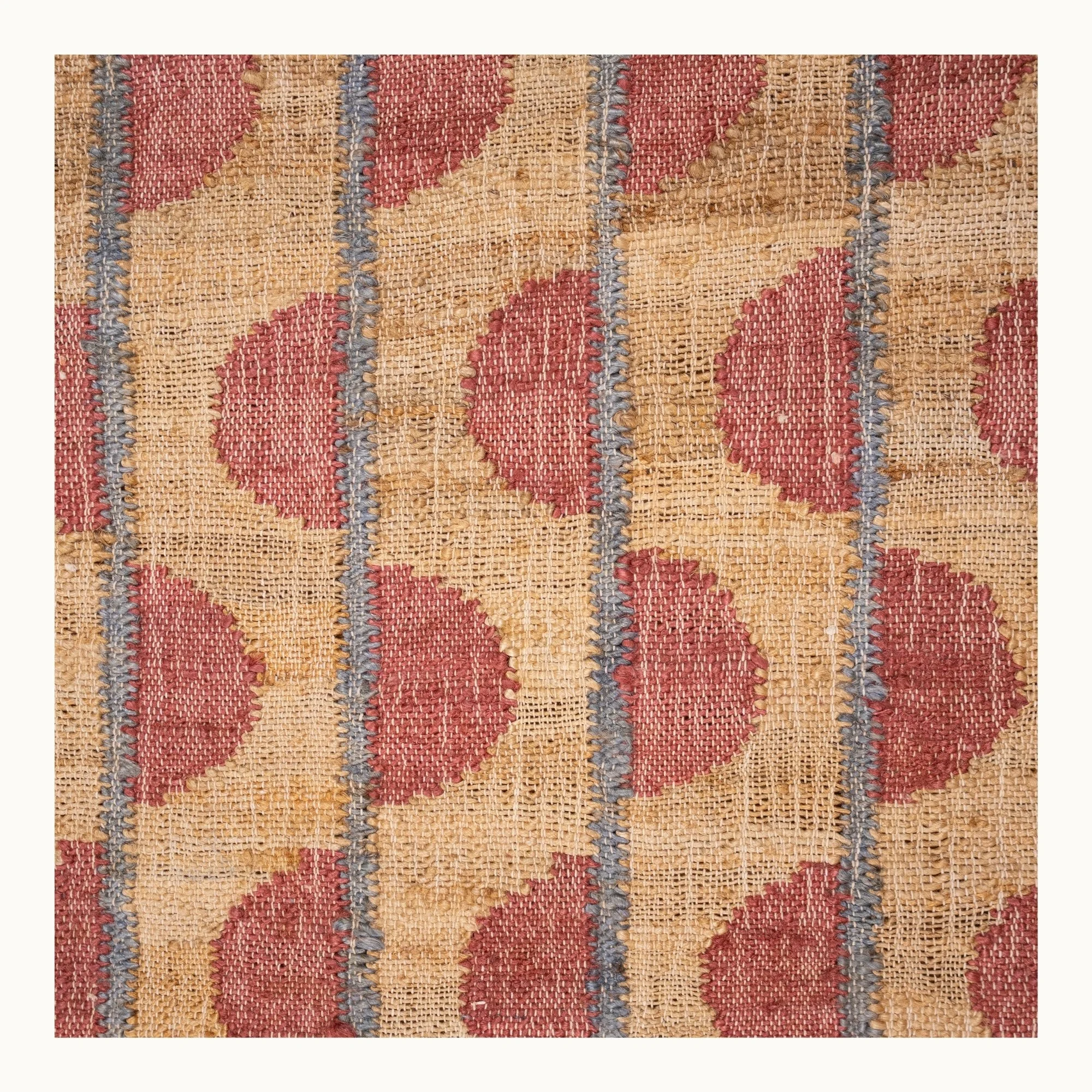 Handwoven jute rug with repeating half-moon pattern in dusty rose and natural sand tones.