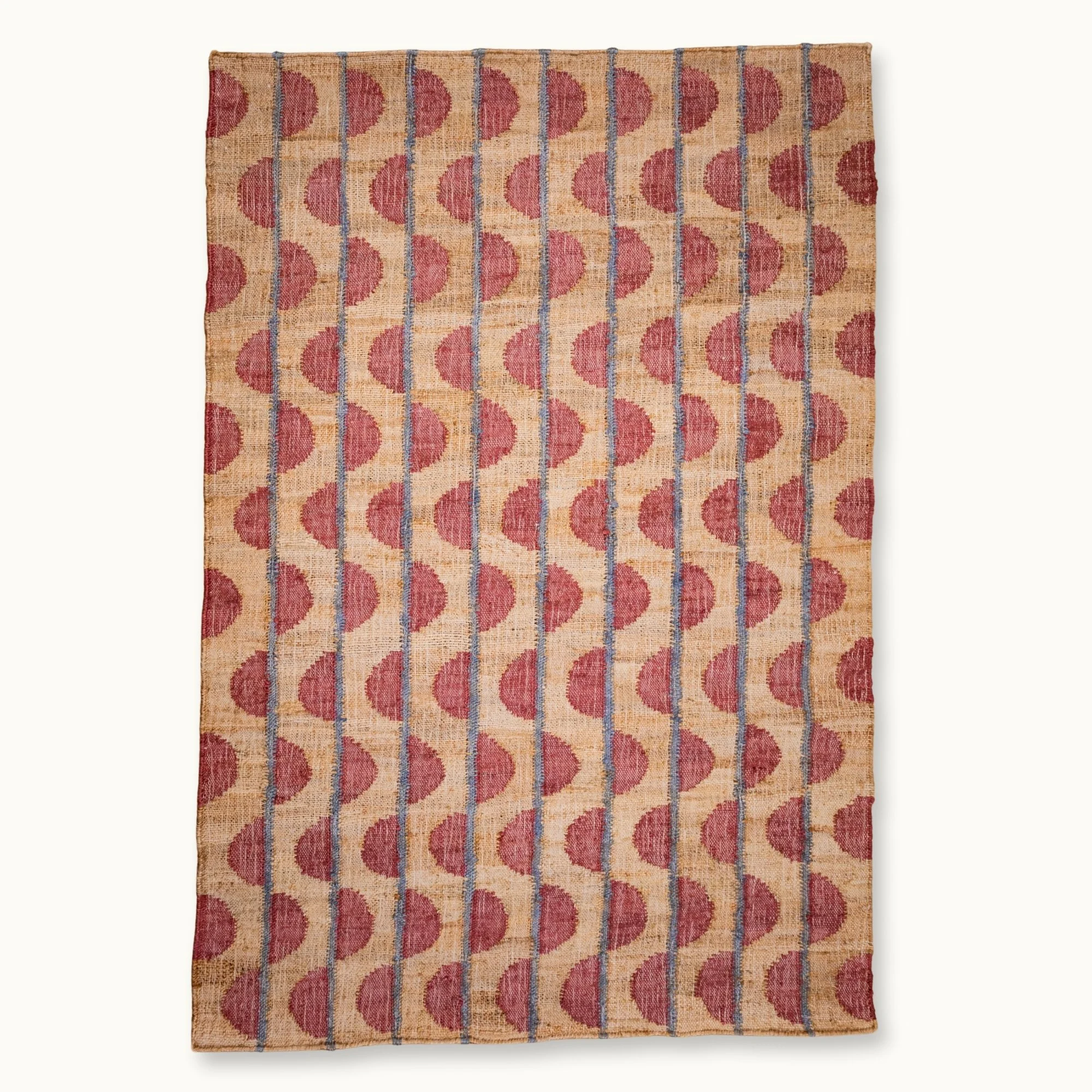 Handwoven jute rug with repeating half-moon pattern in dusty rose and natural sand tones.