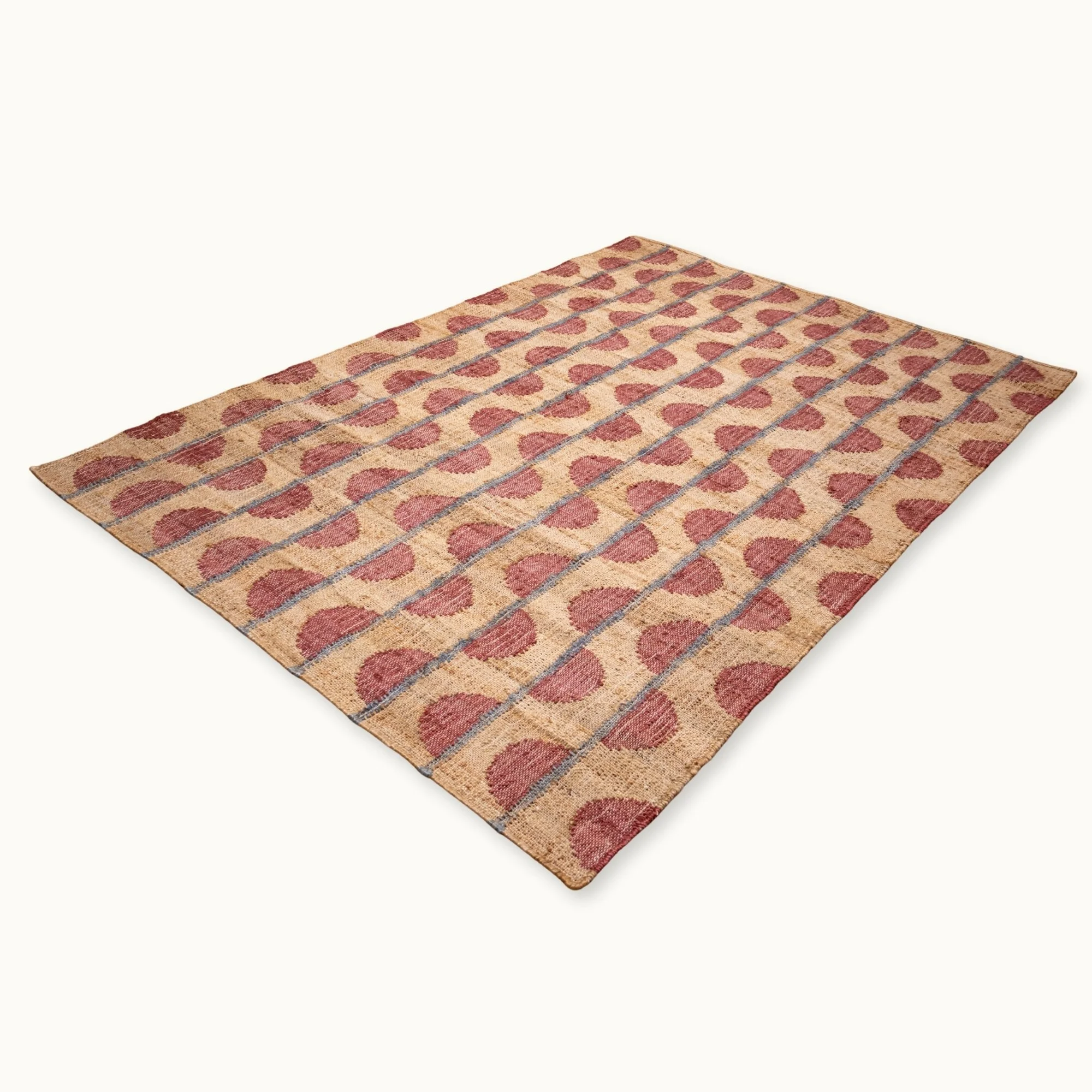 Handwoven jute rug with repeating half-moon pattern in dusty rose and natural sand tones.