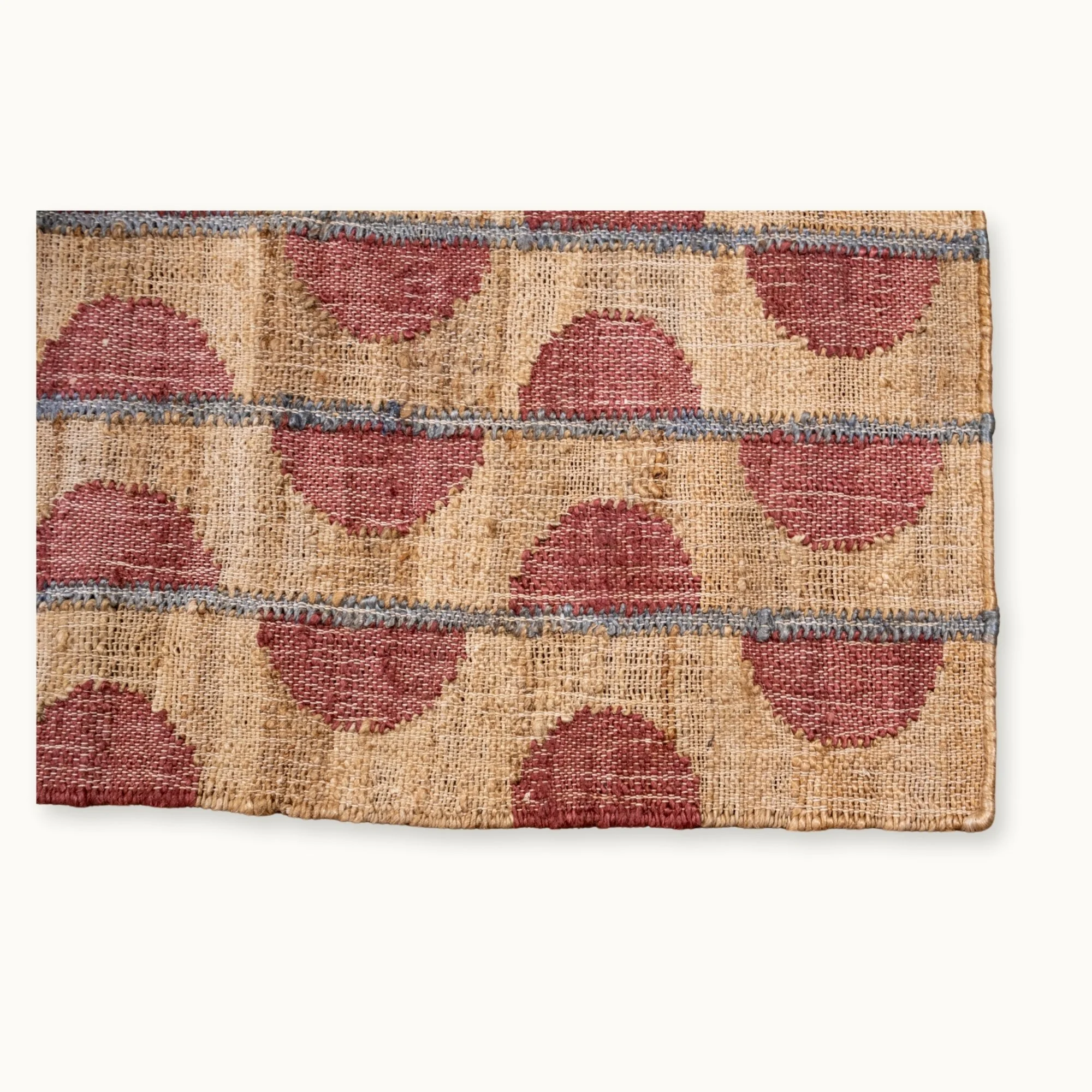 Handwoven jute rug with repeating half-moon pattern in dusty rose and natural sand tones.