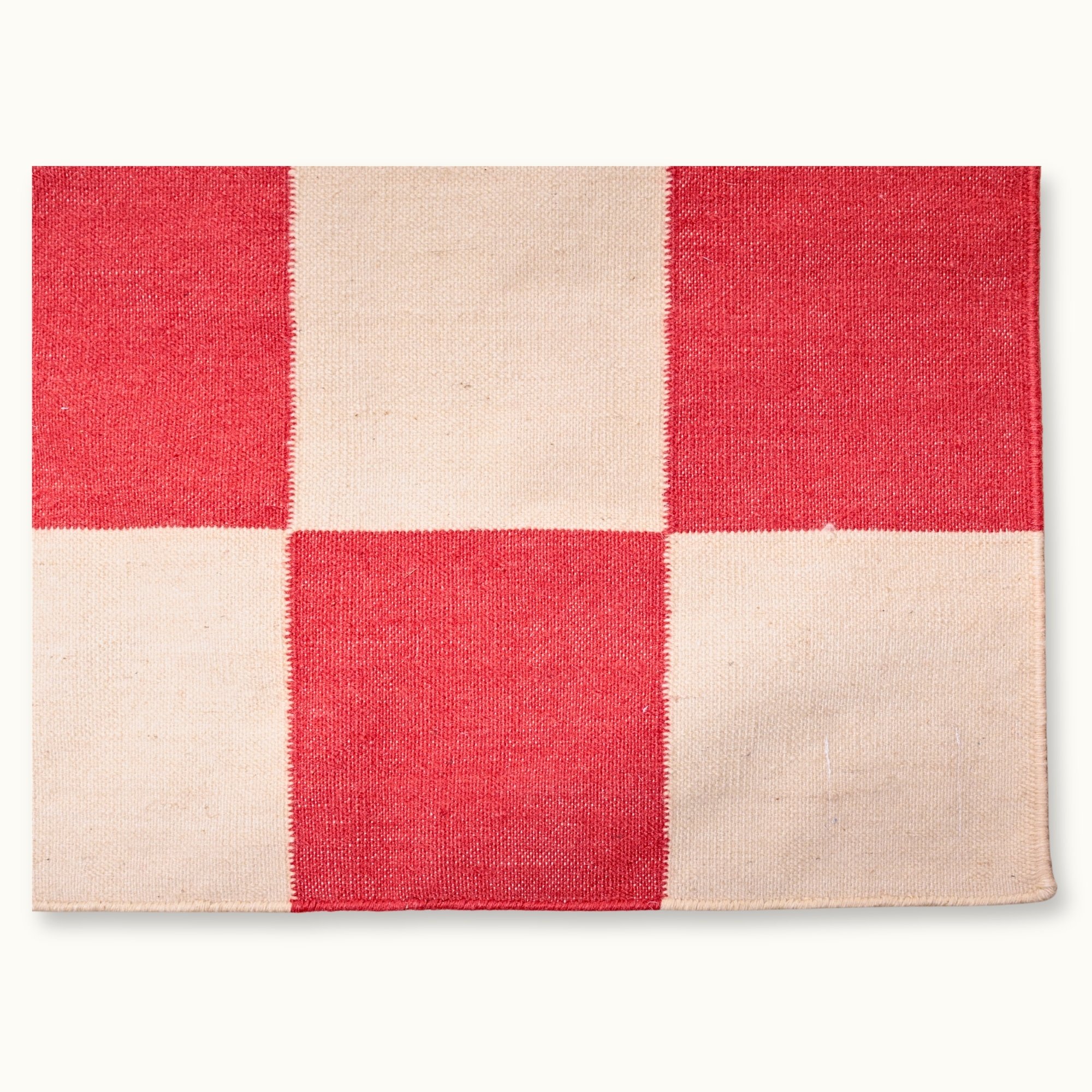 Handwoven wool flatweave rug with checkerboard pattern in red and natural tones