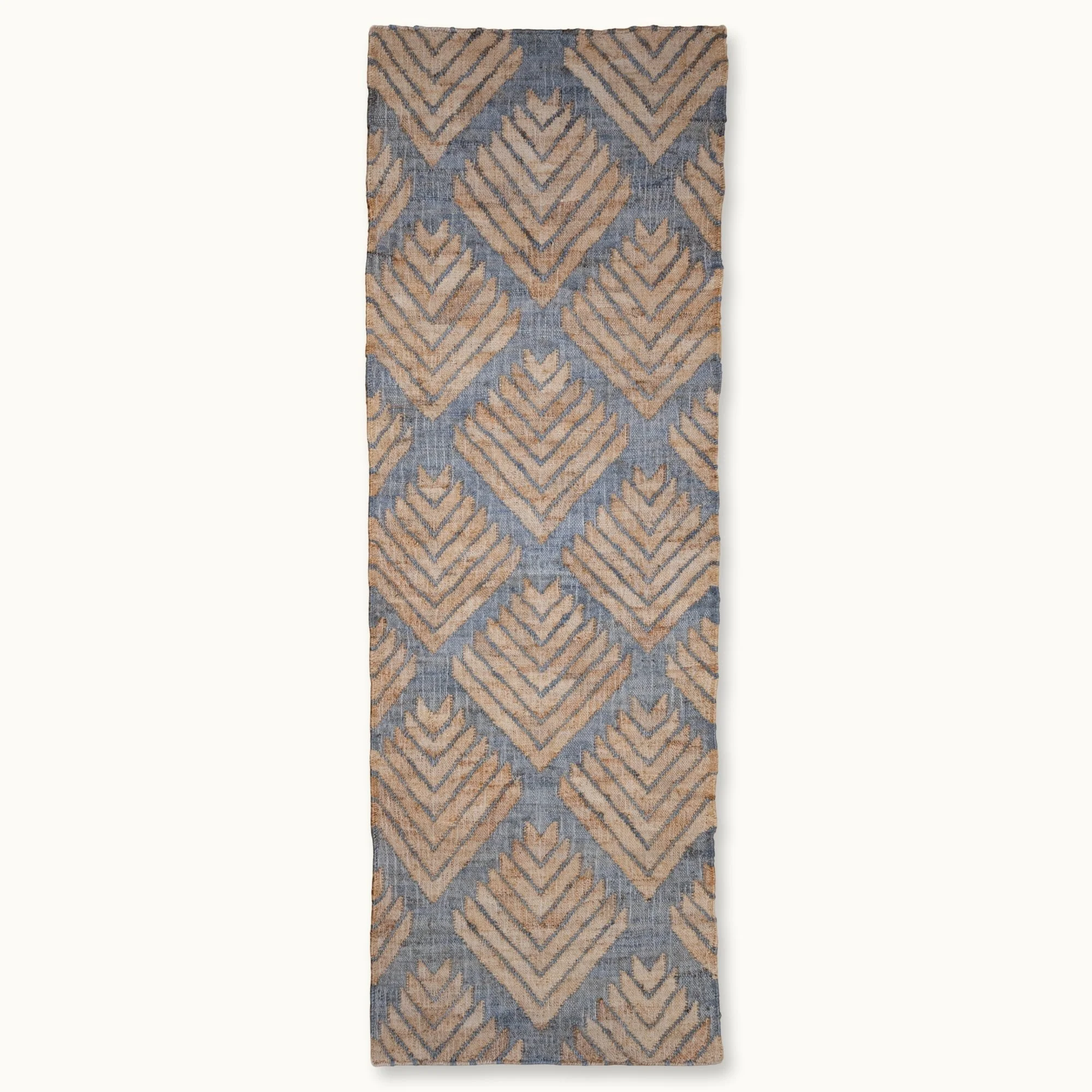 Handgeweven jute loper met een platgeweven structuur en een geometrisch patroon geïnspireerd op palmbladeren, uitgevoerd in gedempte blauwe en natuurlijke zandtinten.