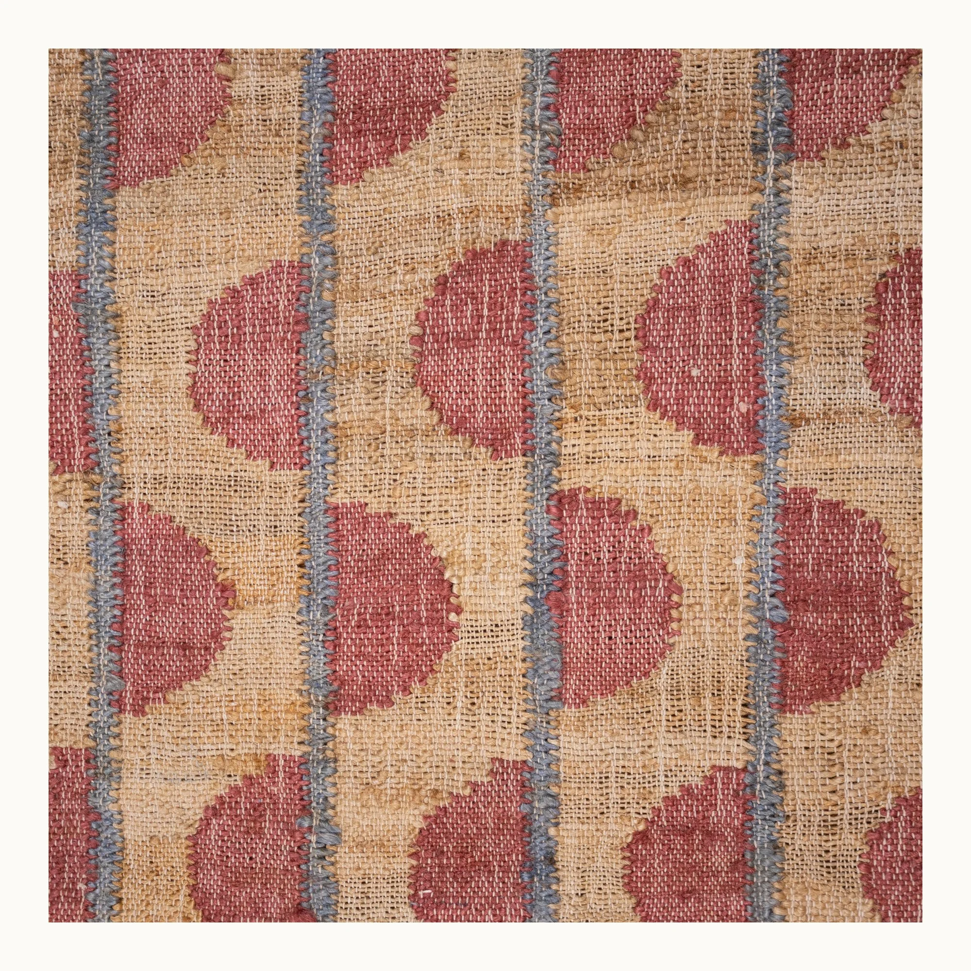 Handwoven jute rug with repeating half-moon pattern in dusty pink and natural sand tones.
