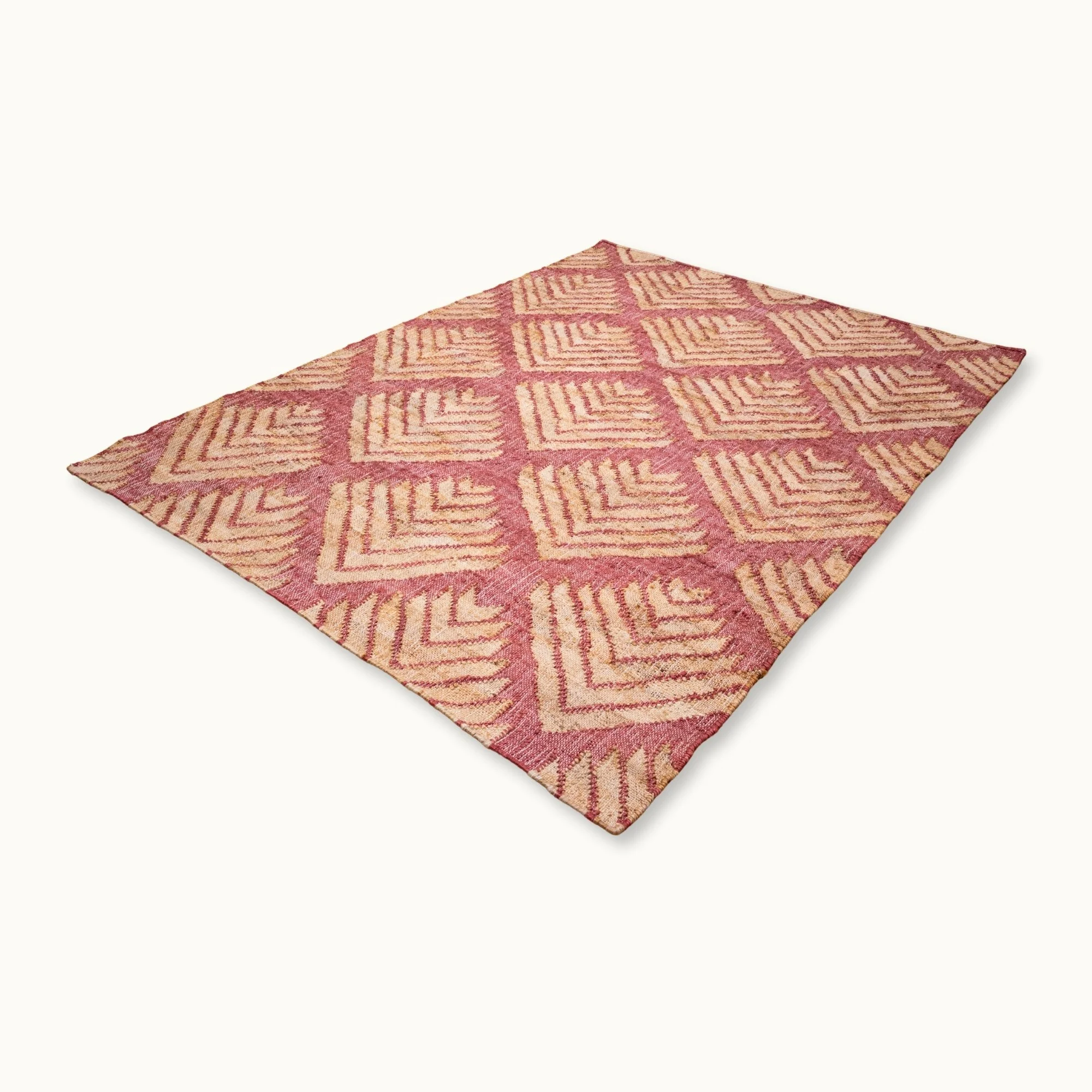 Handgeweven jute vloerkleed met een gestructureerd, op palmbladeren geïnspireerd geometrisch patroon in oudroze en natuurlijke zandtinten.