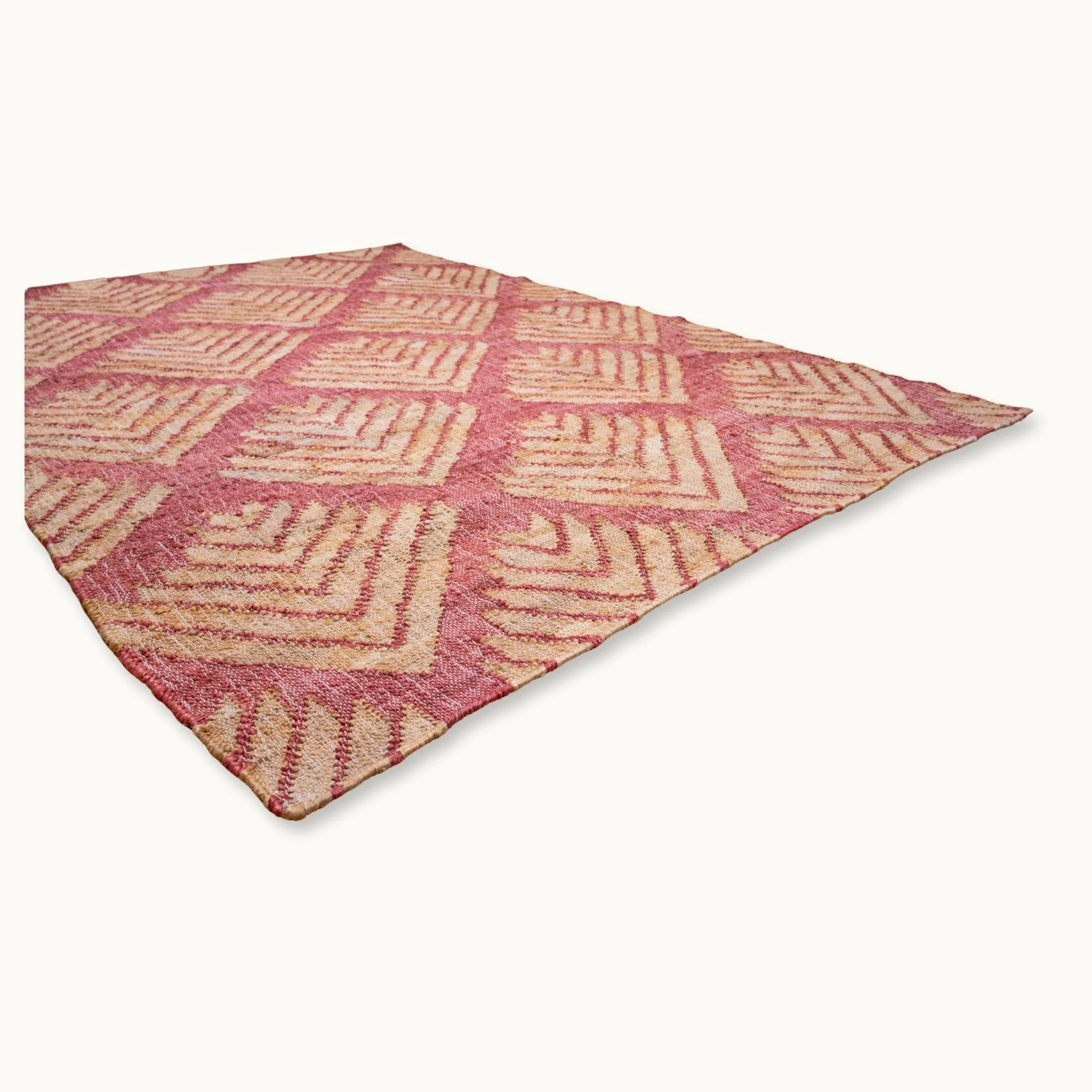Handgeweven jute vloerkleed met een gestructureerd, op palmbladeren geïnspireerd geometrisch patroon in oudroze en natuurlijke zandtinten.