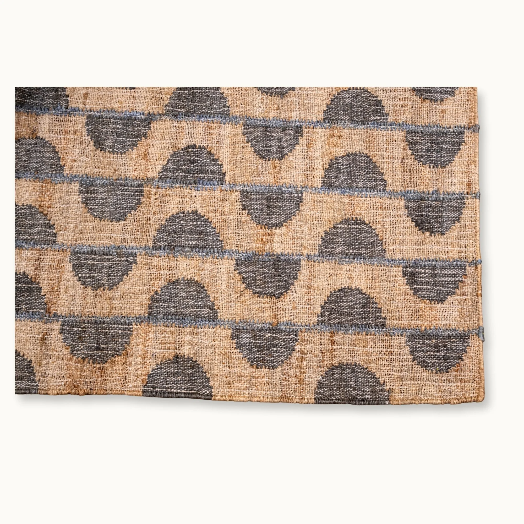 Handwoven jute rug with repeating half-moon pattern in muted olive green and natural sand tones.