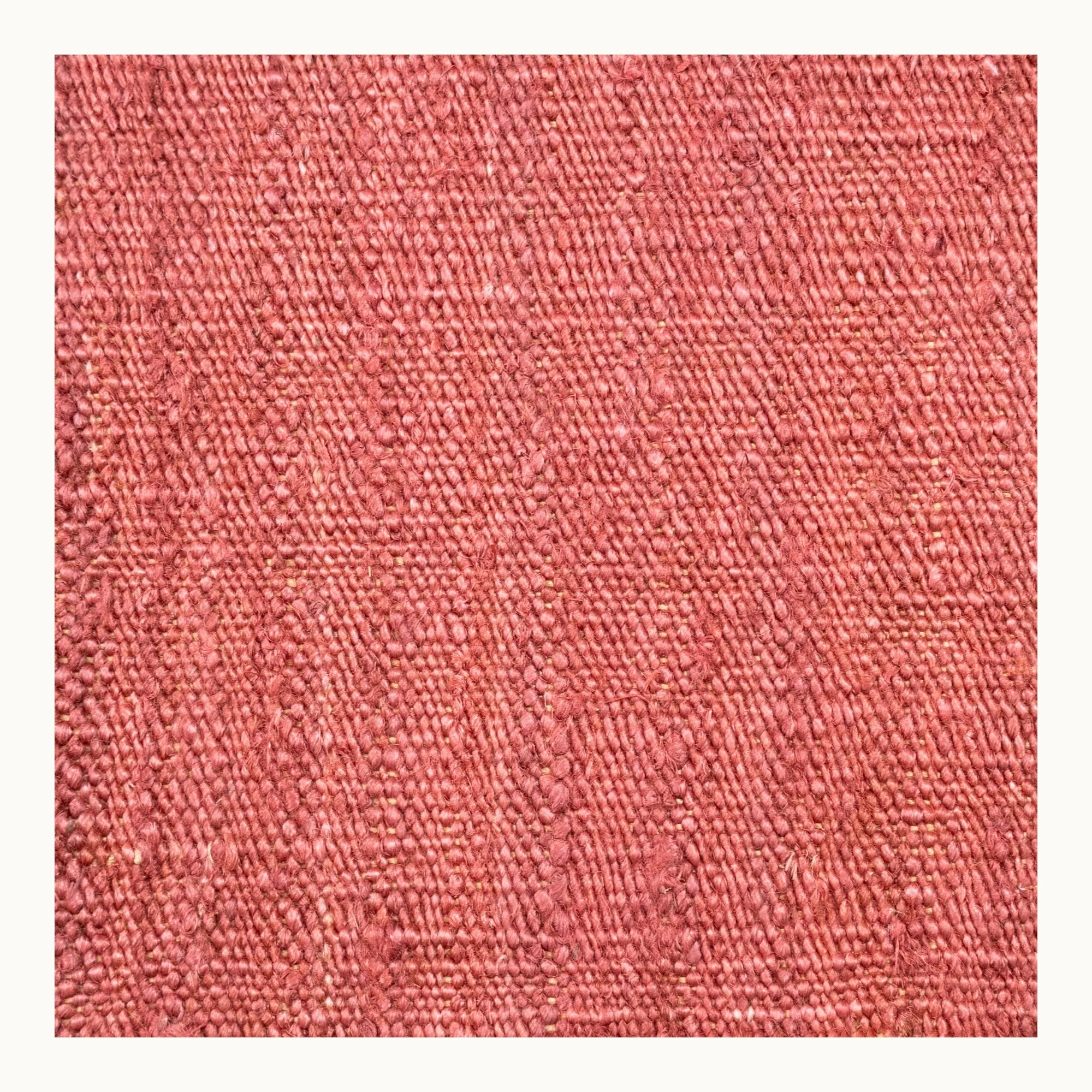 Een eenvoudig, handgeweven jute vloerkleed in zachte, oudroze tinten met een subtiele natuurlijke structuur.