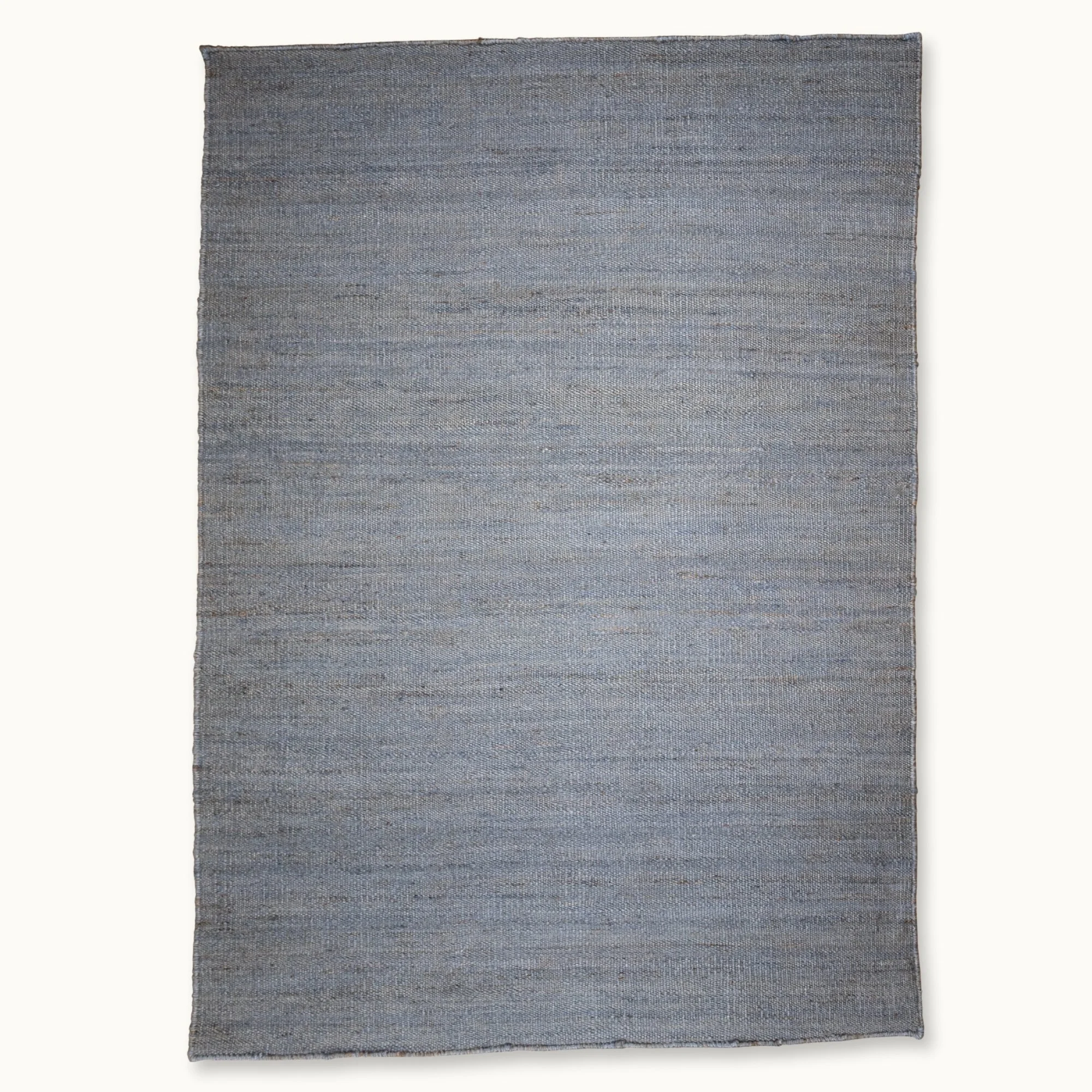 Een eenvoudig, handgeweven jute vloerkleed in ingetogen blauwtinten met een subtiele natuurlijke structuur.