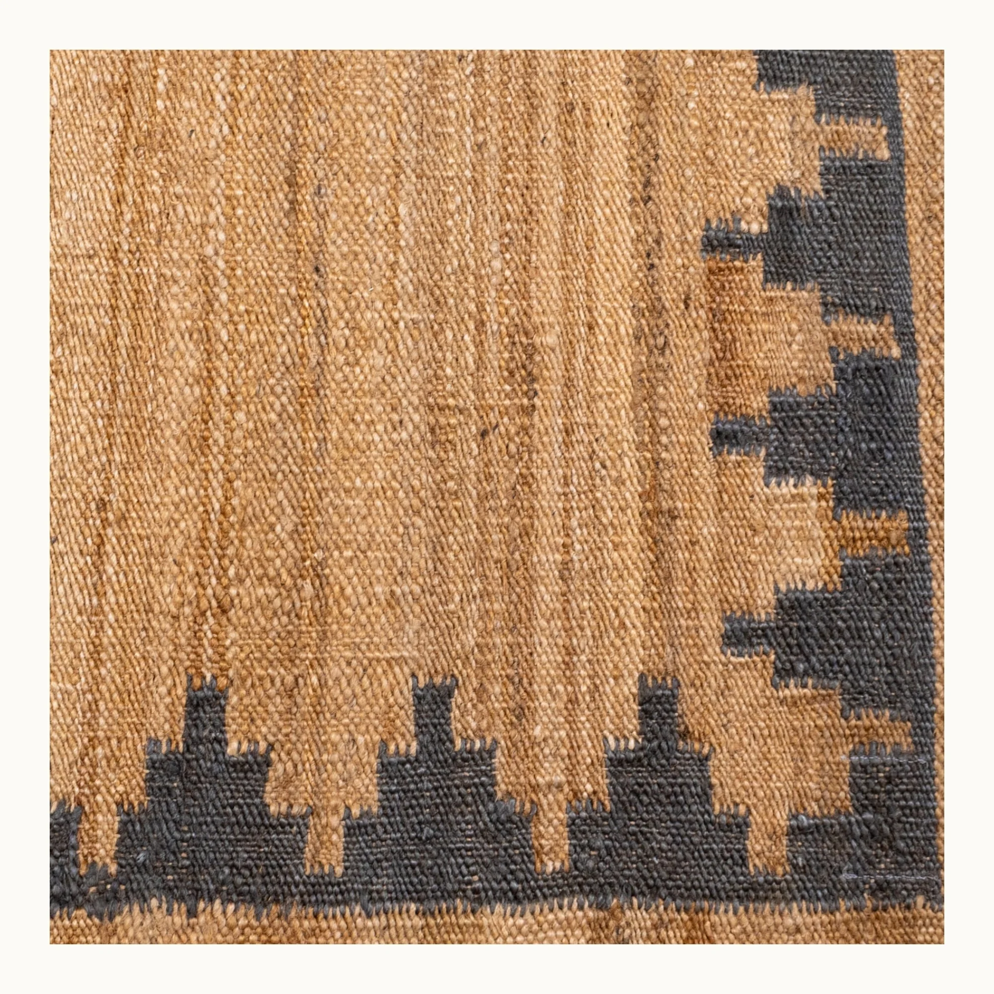 Handgeweven jute vloerkleed met een trapsgewijze geometrische rand in ingetogen olijfgroene en natuurlijke zandtinten.