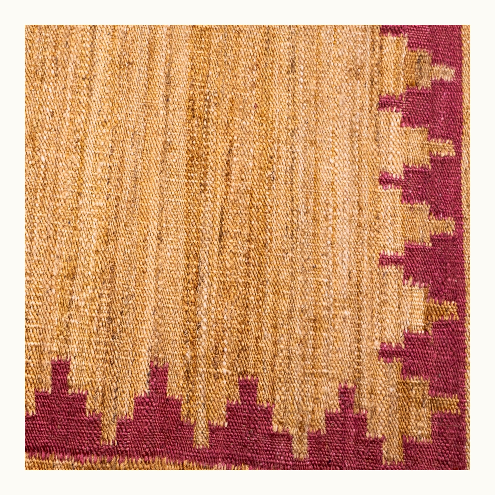 Handgeweven jute vloerkleed met een trapsgewijze geometrische rand in ingetogen roze en natuurlijke zandtinten.