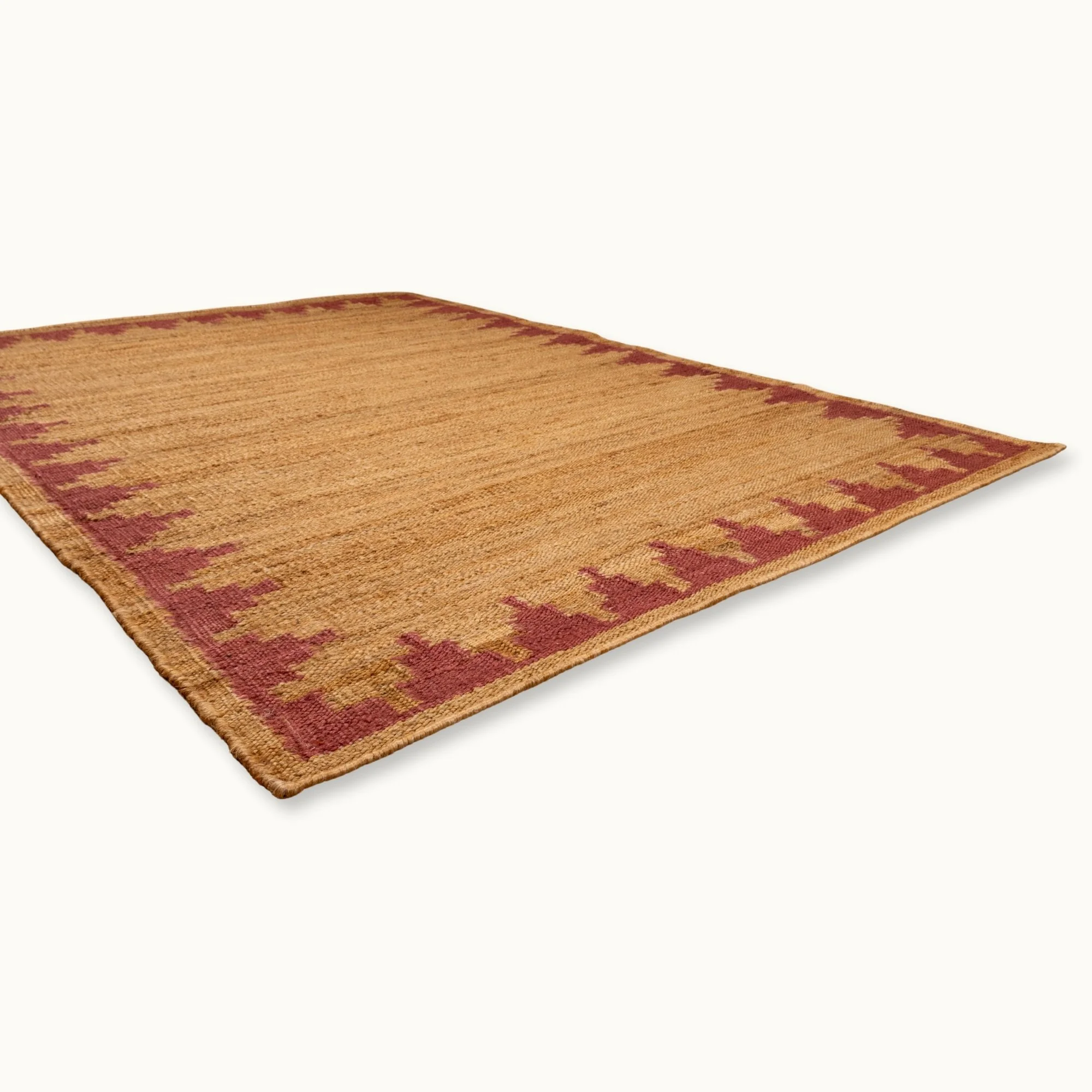 Handgeweven jute vloerkleed met een trapsgewijze geometrische rand in ingetogen roze en natuurlijke zandtinten.
